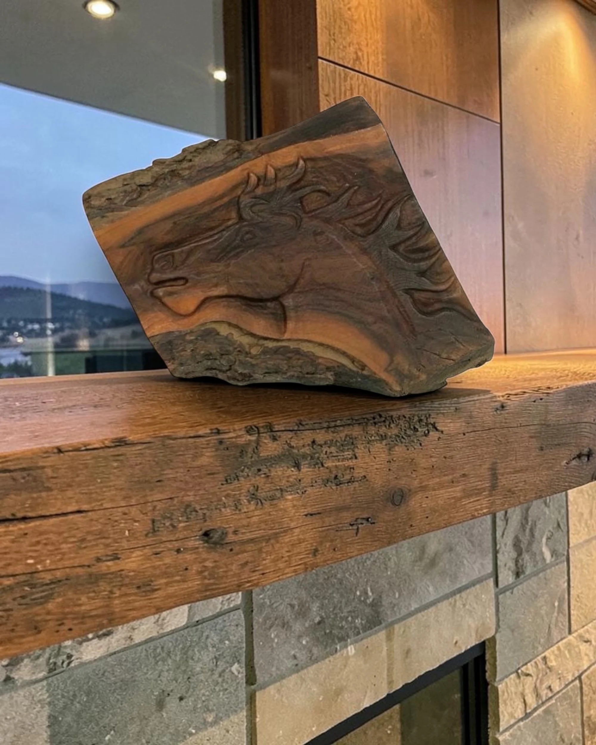 Hand-carved wooden horse head plaque styled on a stone fireplace mantel in a modern ranch-style living room
