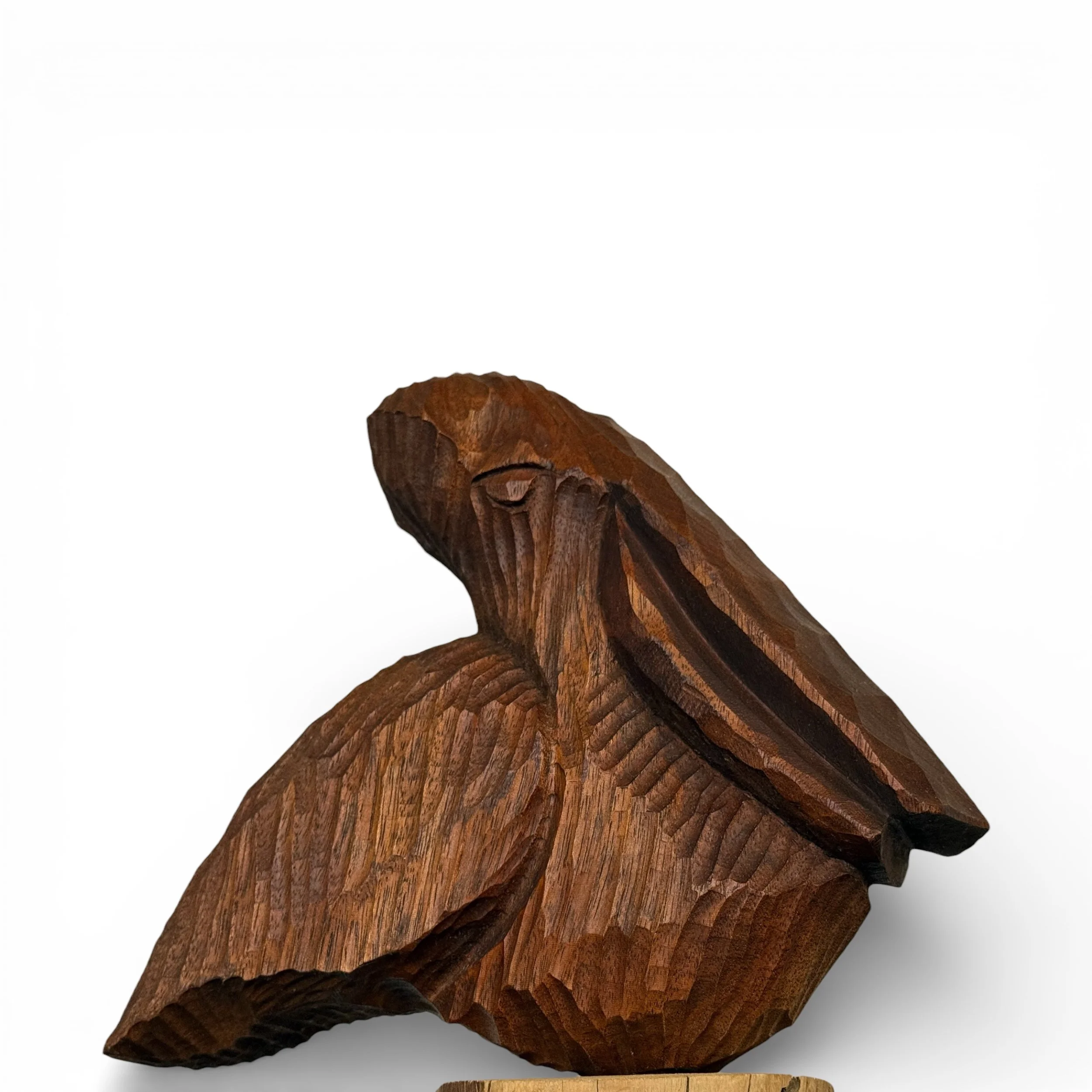 Close up view of vintage hand carved wooden pelican statue on a log detailing wood grain