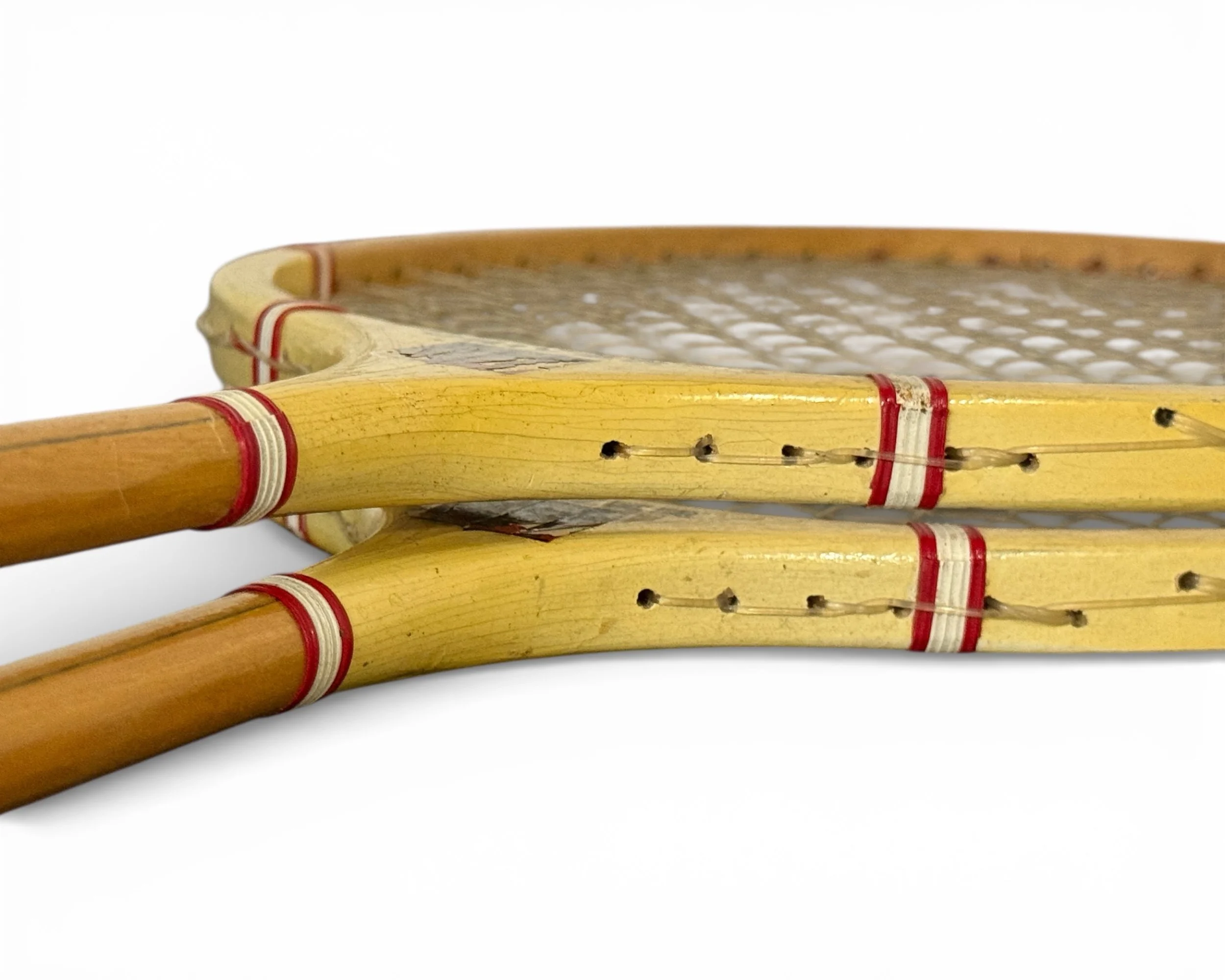 side angle close up view of head on pair of vintage wooden badminton rackets