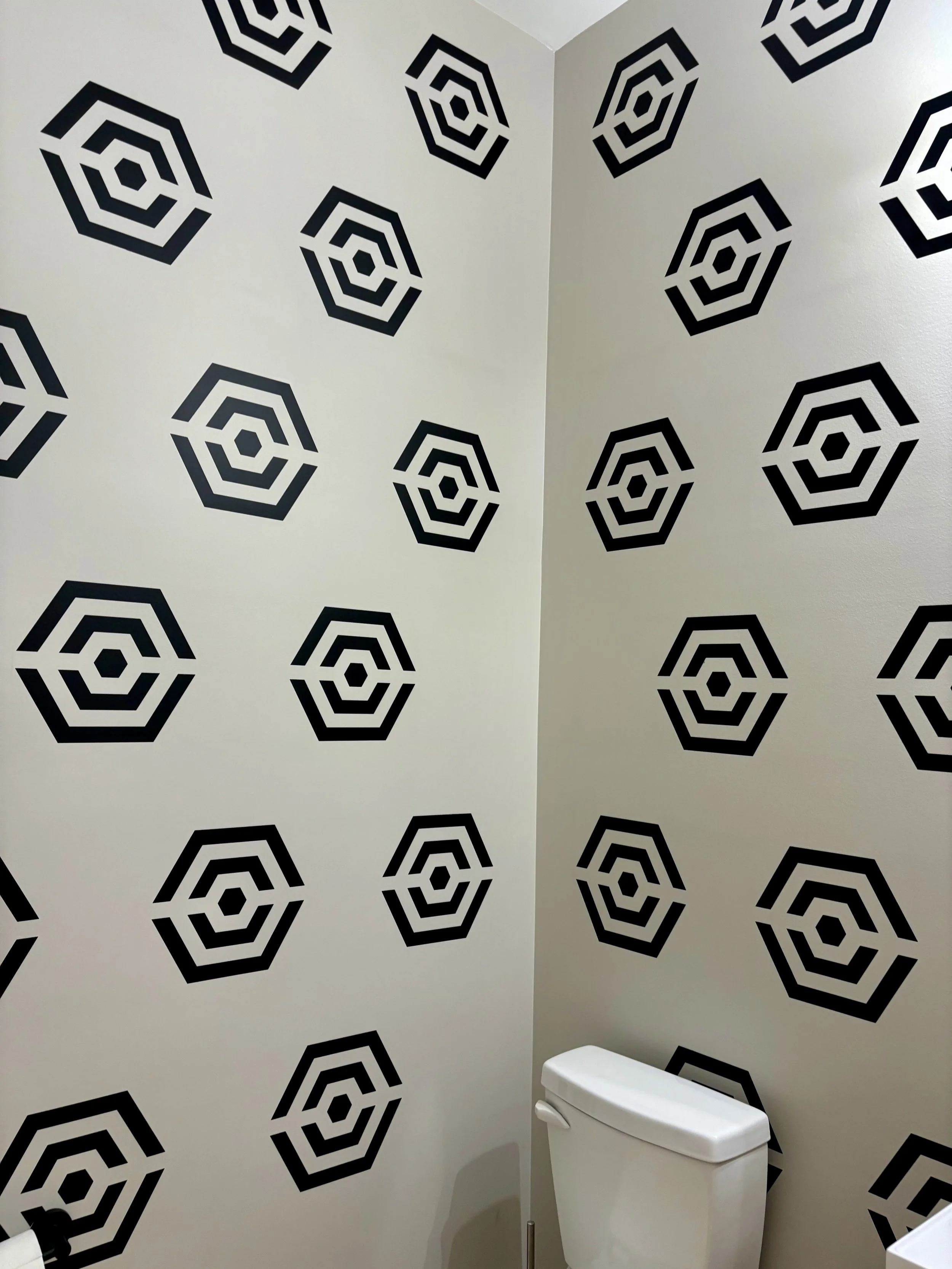 Geometric hexagon pattern wall decals by Wall Star Graphics shown in black on a white wall of a bathroom.