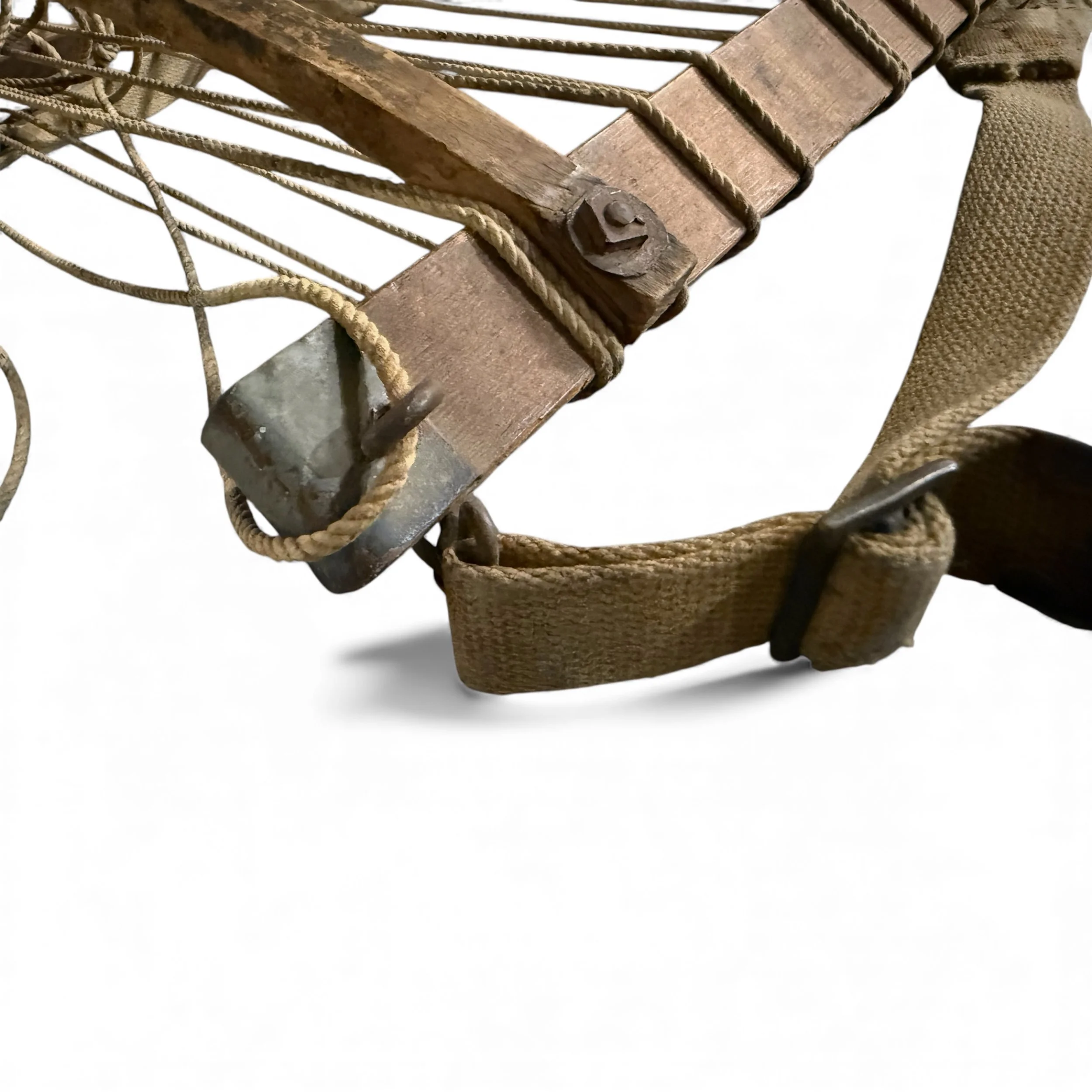 Close-up of vintage wooden packboard frame including details of canvas straps, rope, and metal hardware.