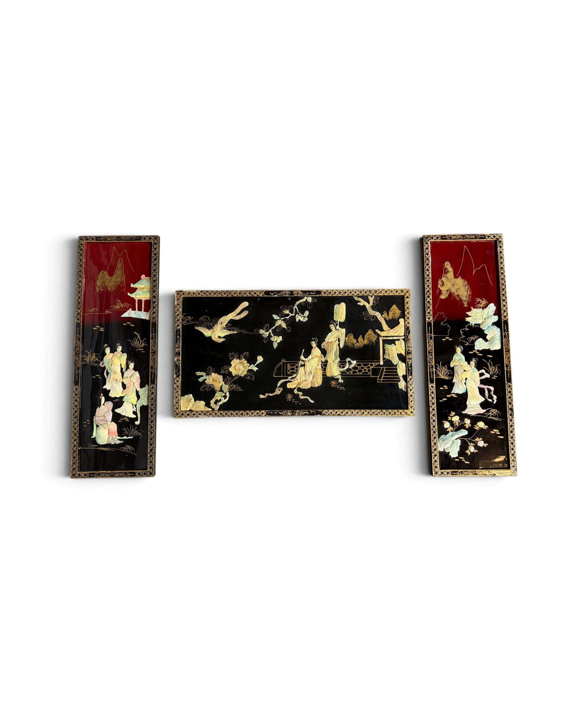 A set of three rectangular wall plaques with black and deep red lacquer finishes. The panels feature inlaid mother-of-pearl figures, floral motifs, and landscape scenes