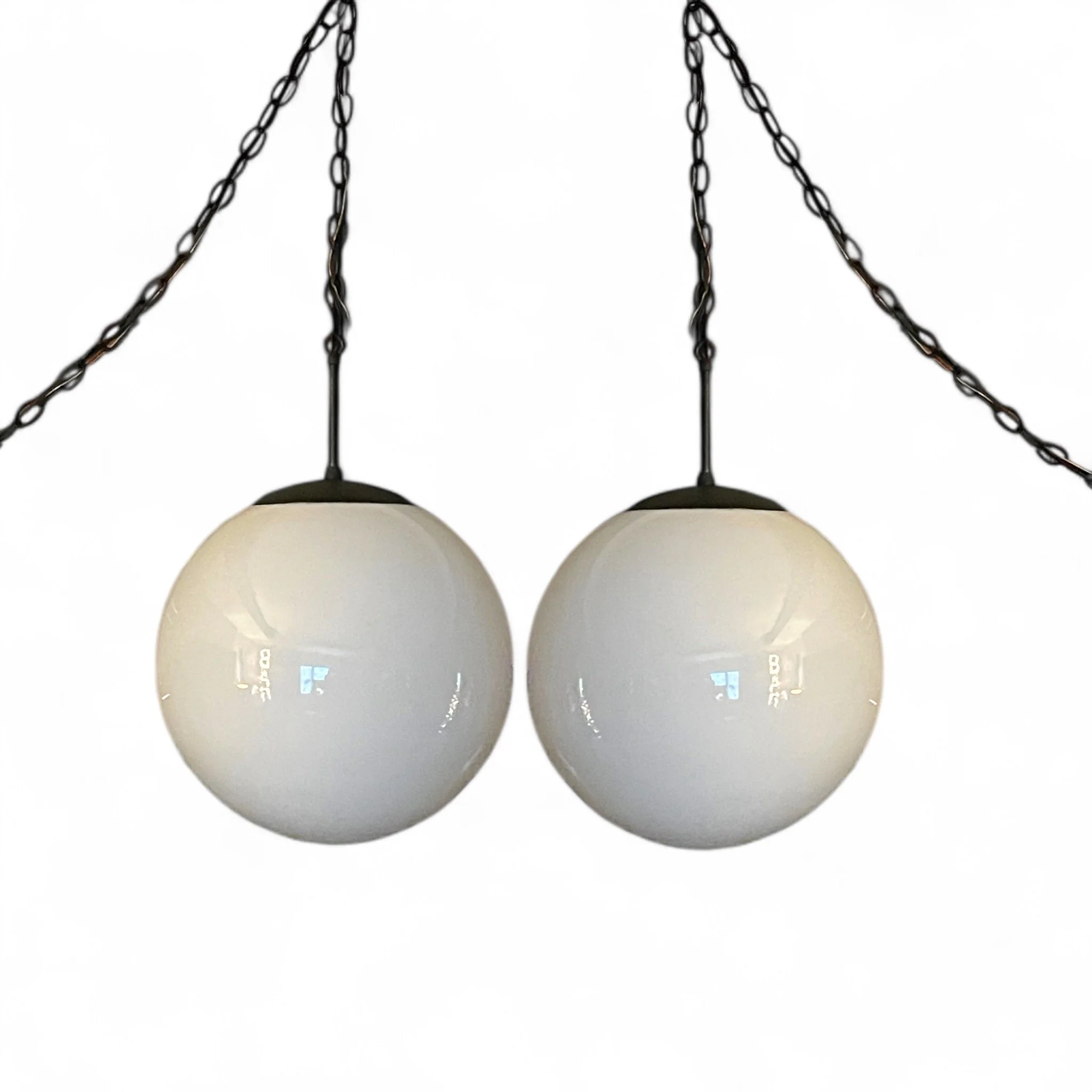Pair of large 1960s white glass orb pendant swag hanging lights with black chain and finial, mid century modern design, perfect for vintage home decor or retro interior lighting.
