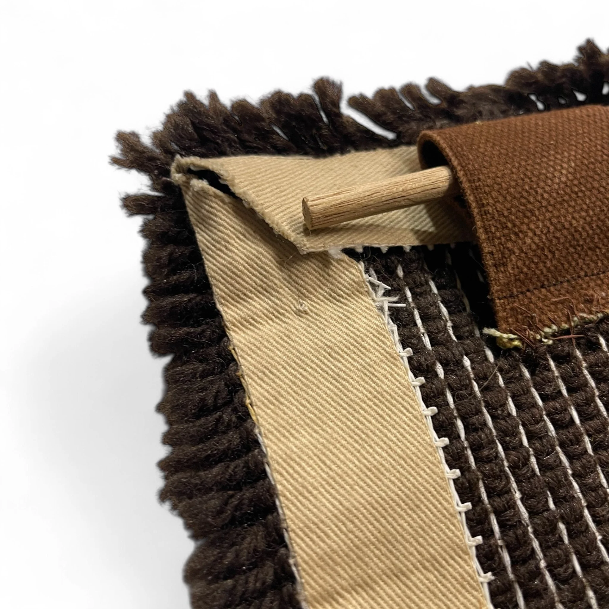 1970s vintage latch hook rug wall hanging featuring a mountain, sun, and tree design in warm earth tones of brown, orange, yellow, and off-white. Retro mid century decor