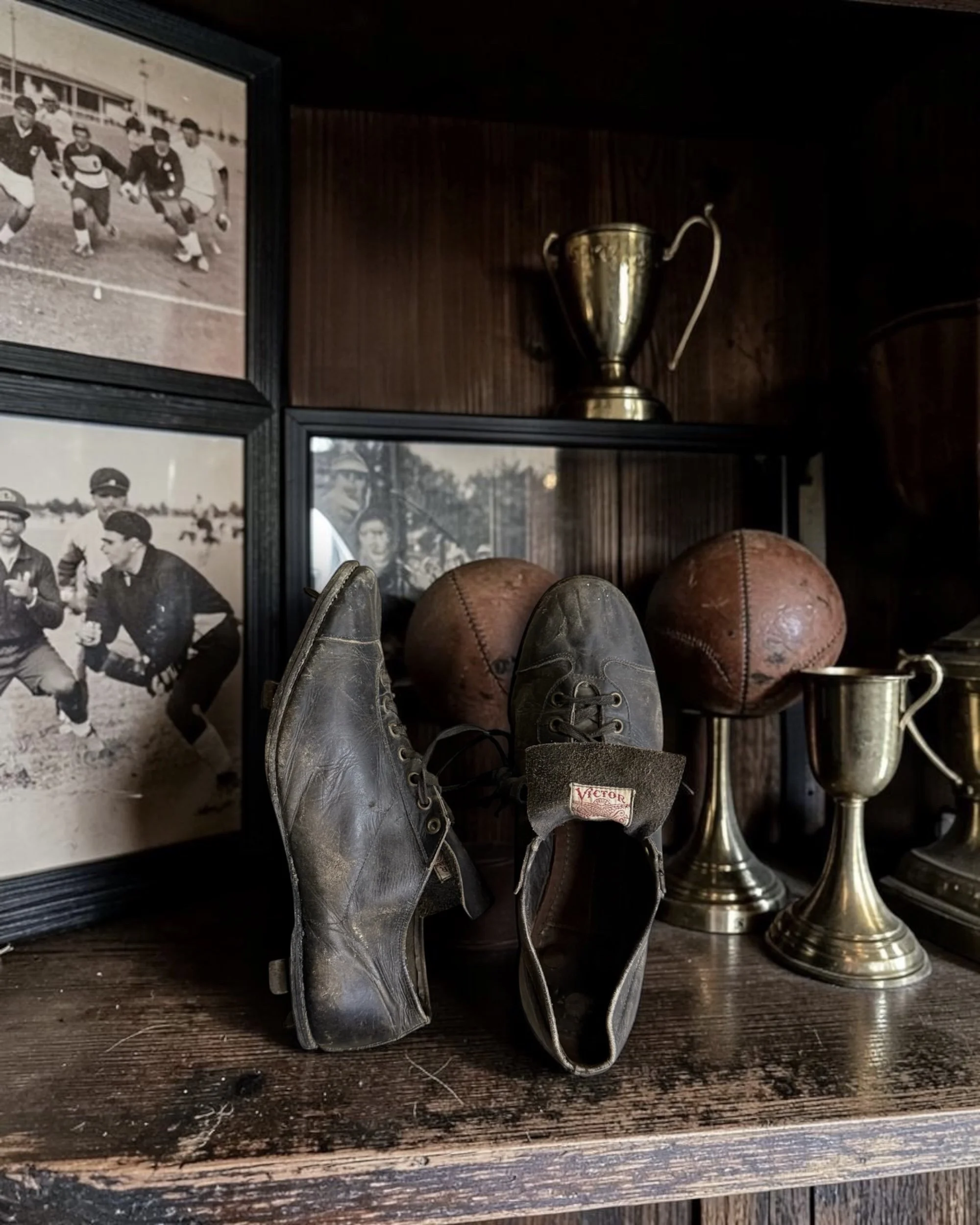 Vintage black leather cleats from the 1920s by Victor Wright & Ditson, shown as a decorative collectible in an old school sports bar