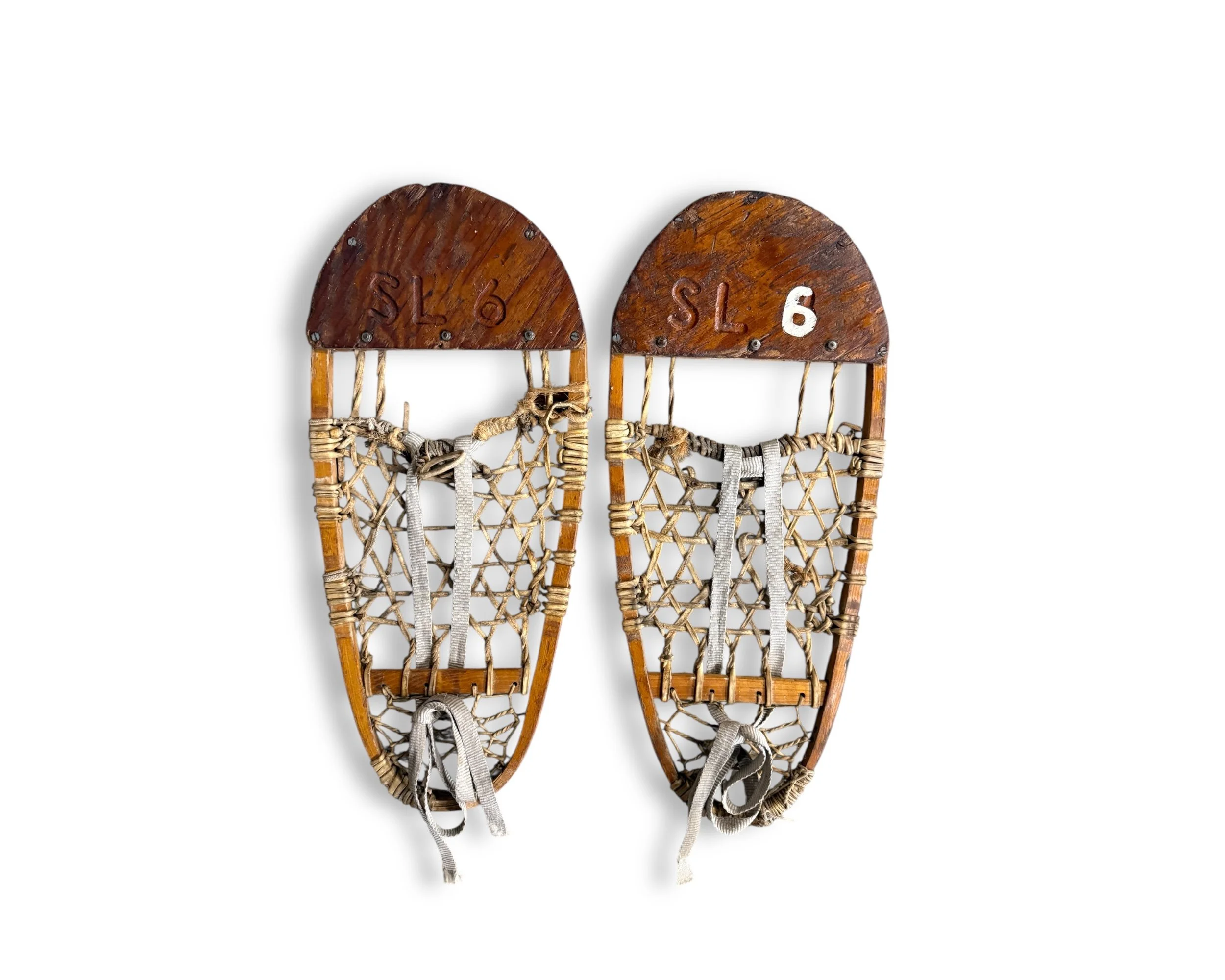 Pair of vintage wooden snowshoes with rawhide webbing on white background