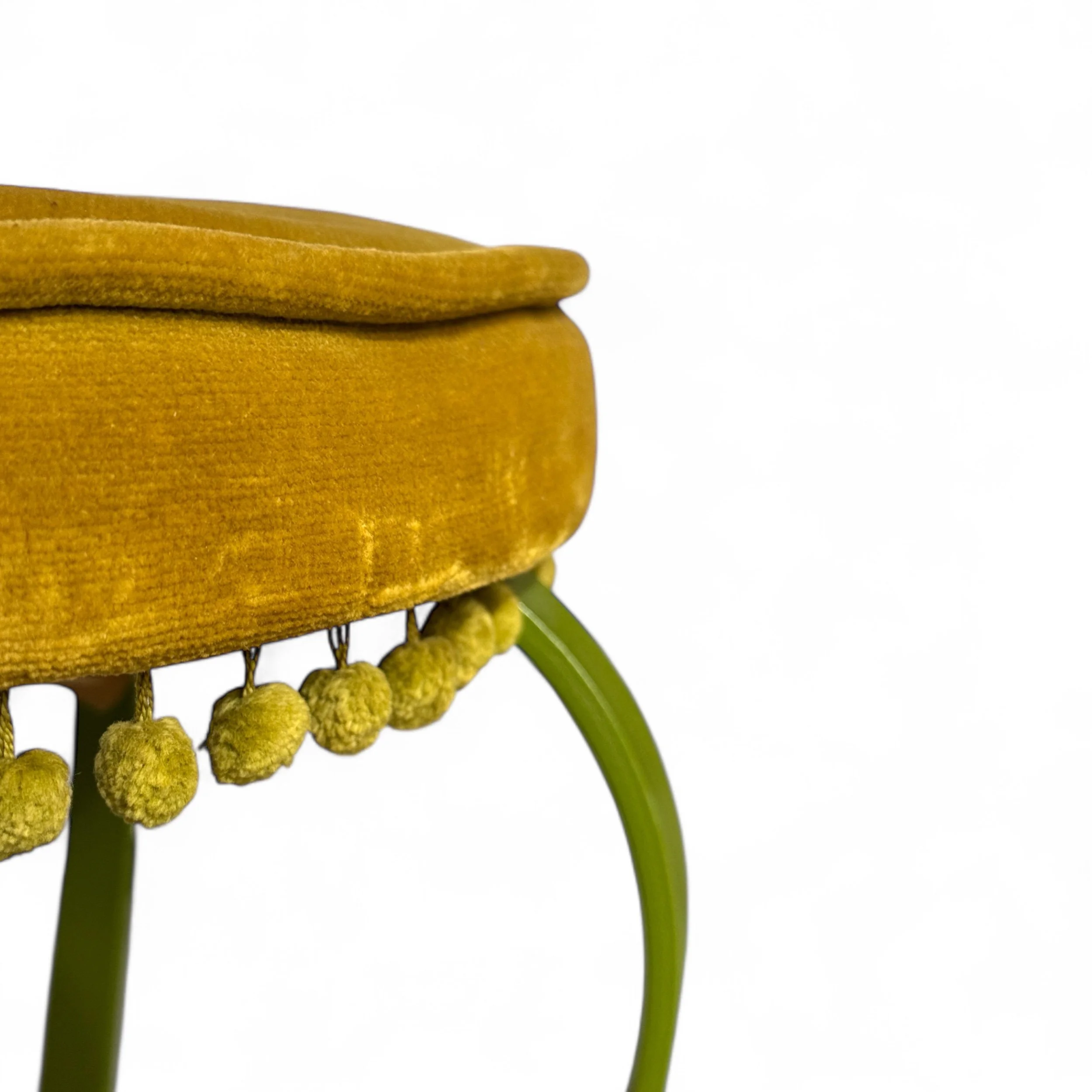 Close-up of pom pom trim on velvet cushion