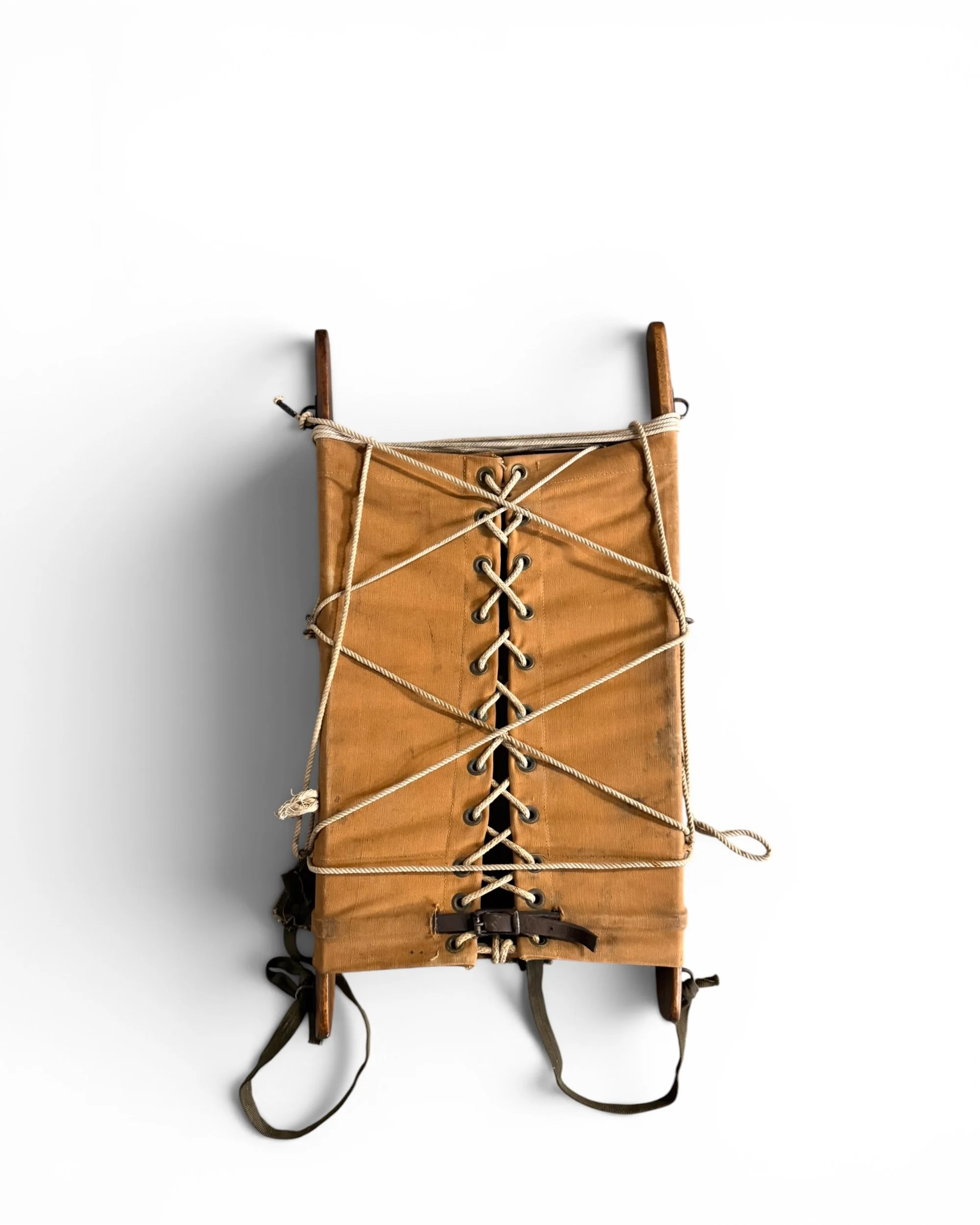 Vintage canvas packboard front view showing wooden frame, rope lacing, grommets, and aged tan canvas construction.