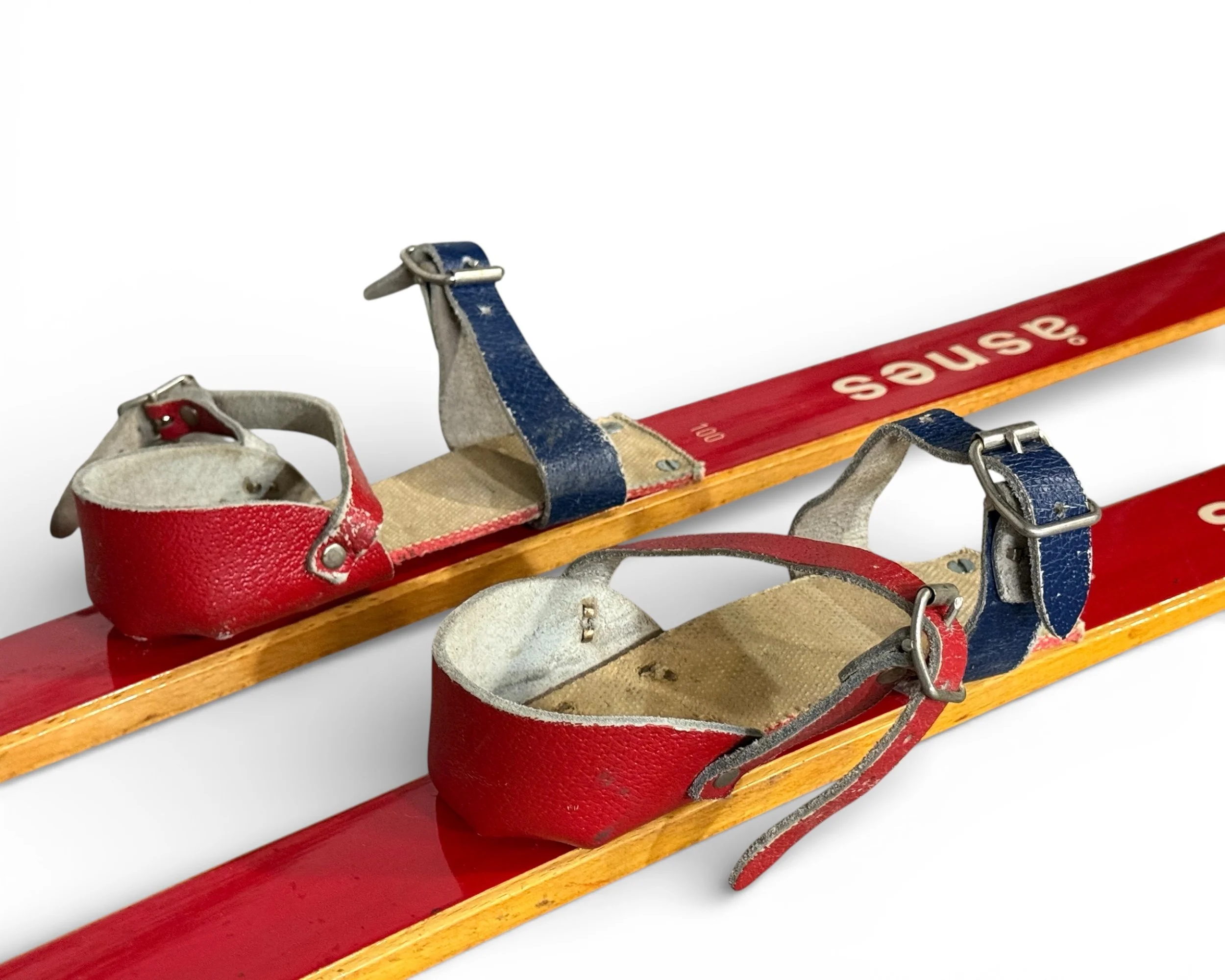 Close up side view of red and blue leather bindings on vintage Norwegian snow skis for kids