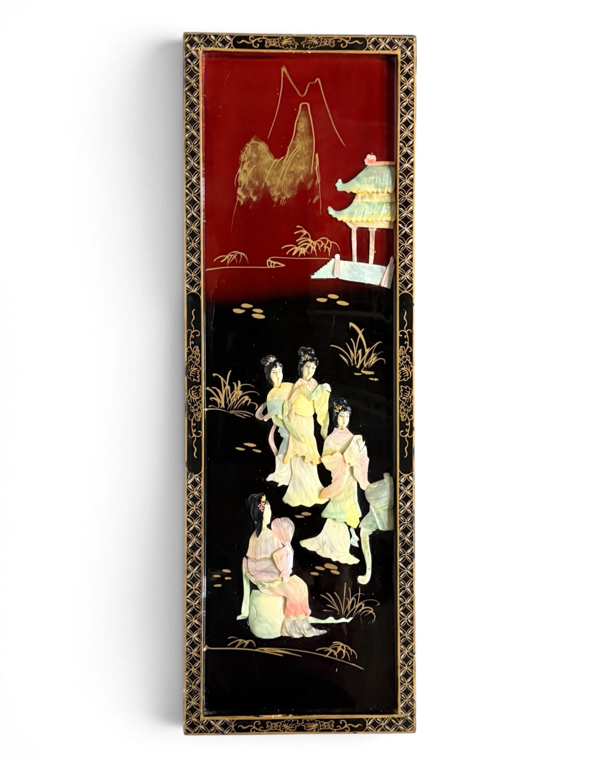 A rectangular wall plaque featuring a black and deep red lacquered surface with gold-painted border details. The center displays a raised relief mother of pearl scene