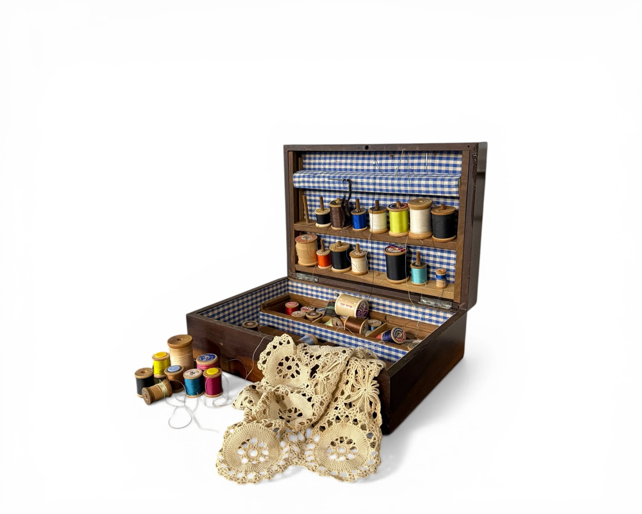 Vintage wooden sewing box open with thread spools and gingham lining
