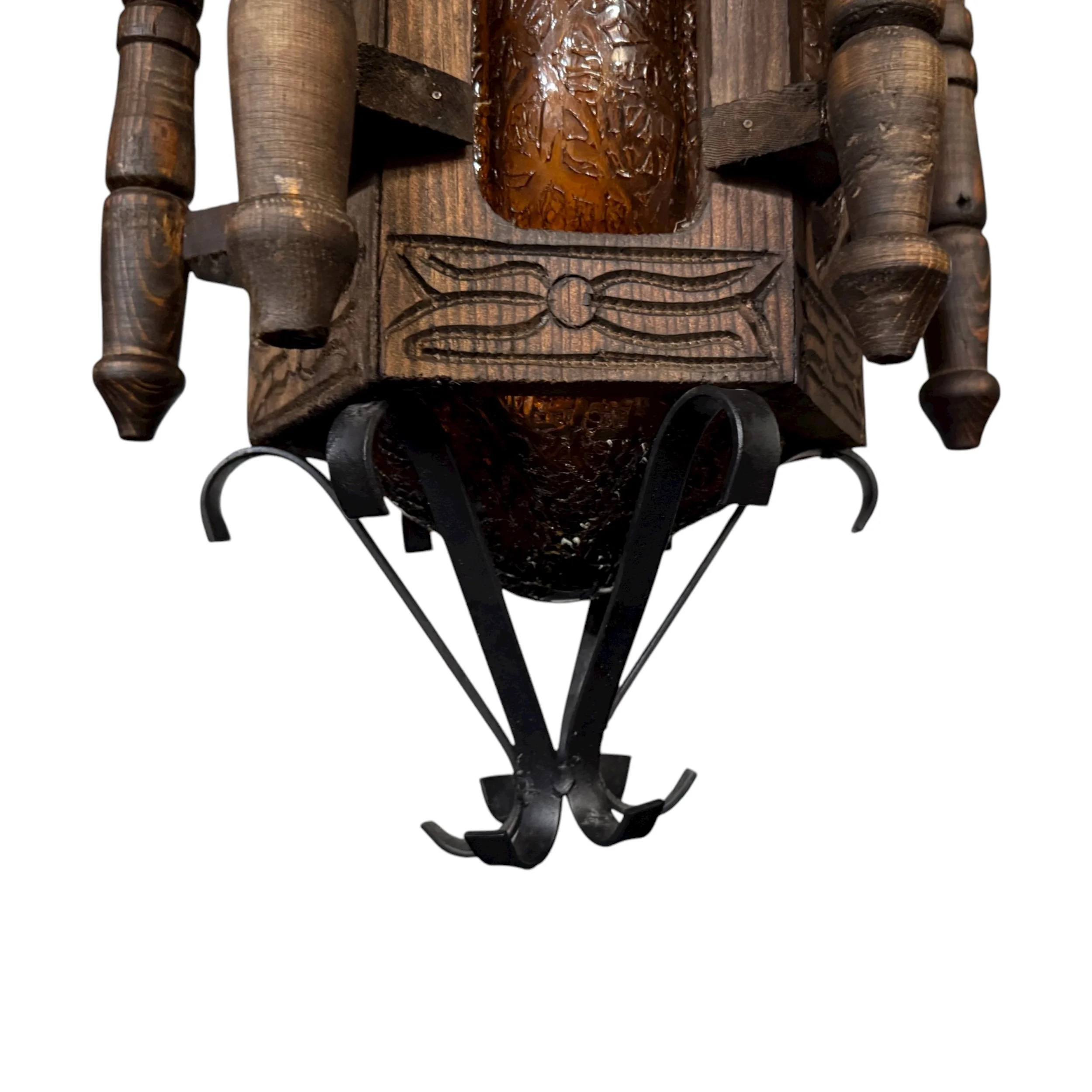 Close up view of bottom portion of a vintage Spanish Revival carved wood and wrought iron hanging lamp with amber glass panels