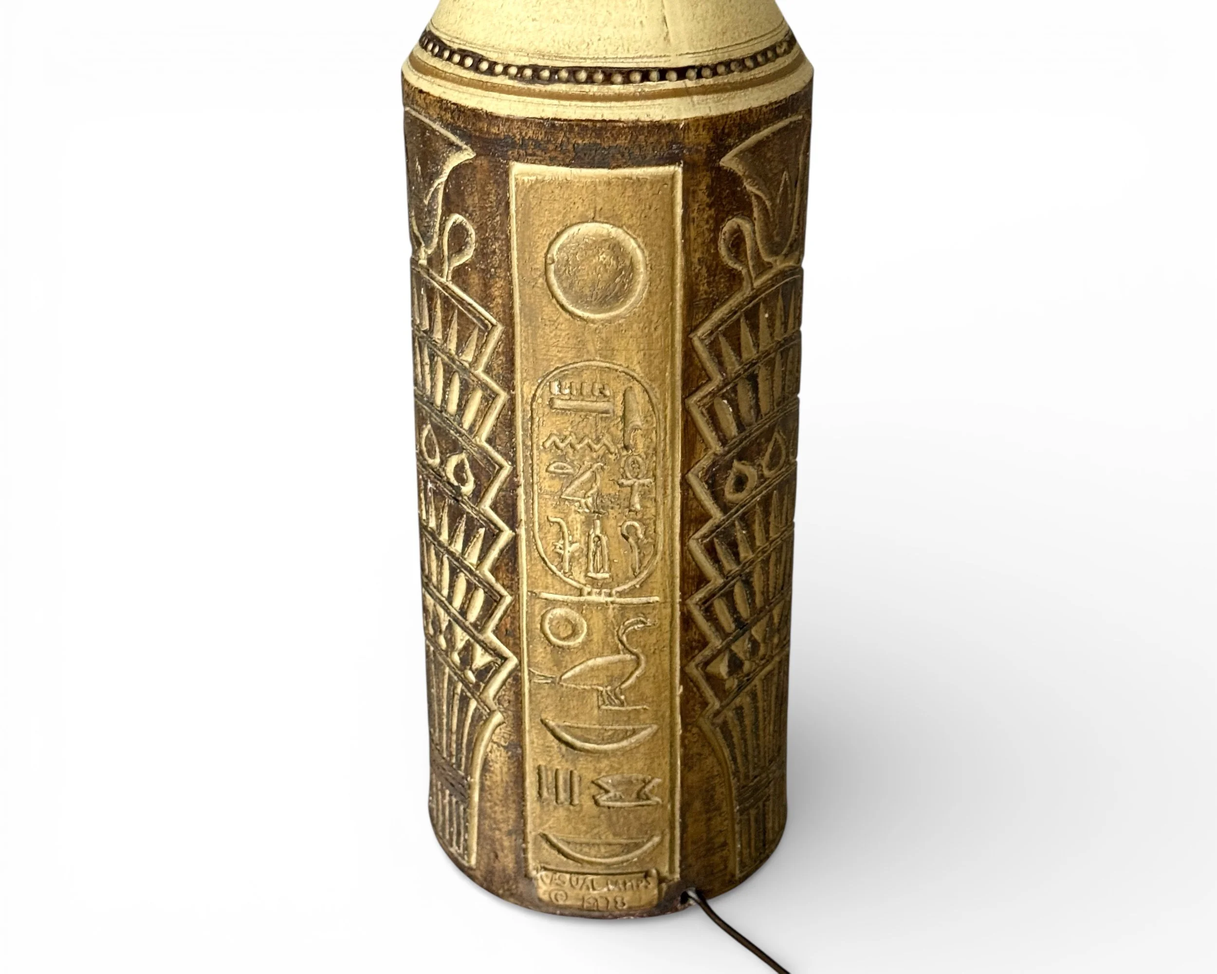 close up view of carved relief pattern that resembles hieroglyphics on vintage ceramic lamp base