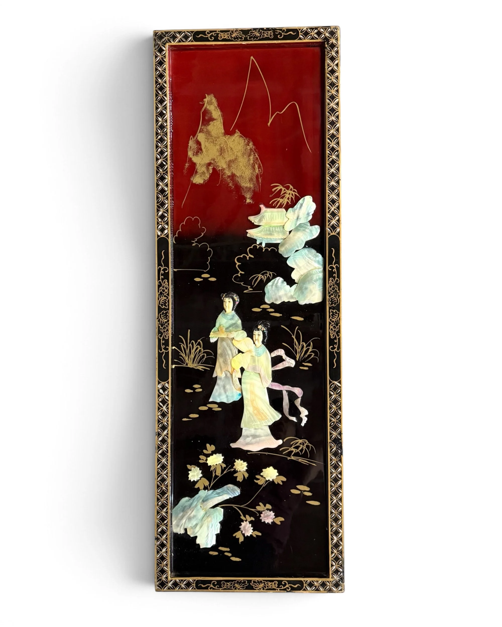 A rectangular wall plaque featuring a black and deep red lacquered surface with gold-painted border details. The center displays a raised mother of pearl relief scene