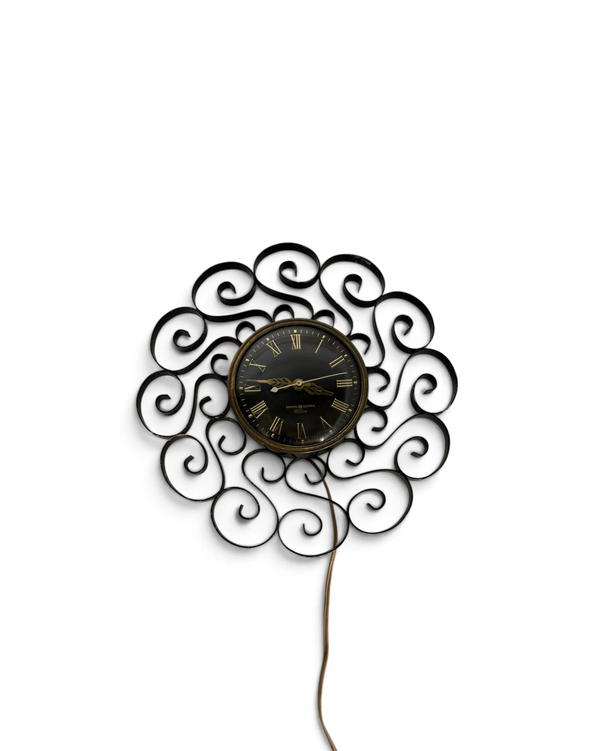 Vintage General Electric Telechron wall mount plug-in clock with black scrollwork frame and mid-century design, gold roman numerals