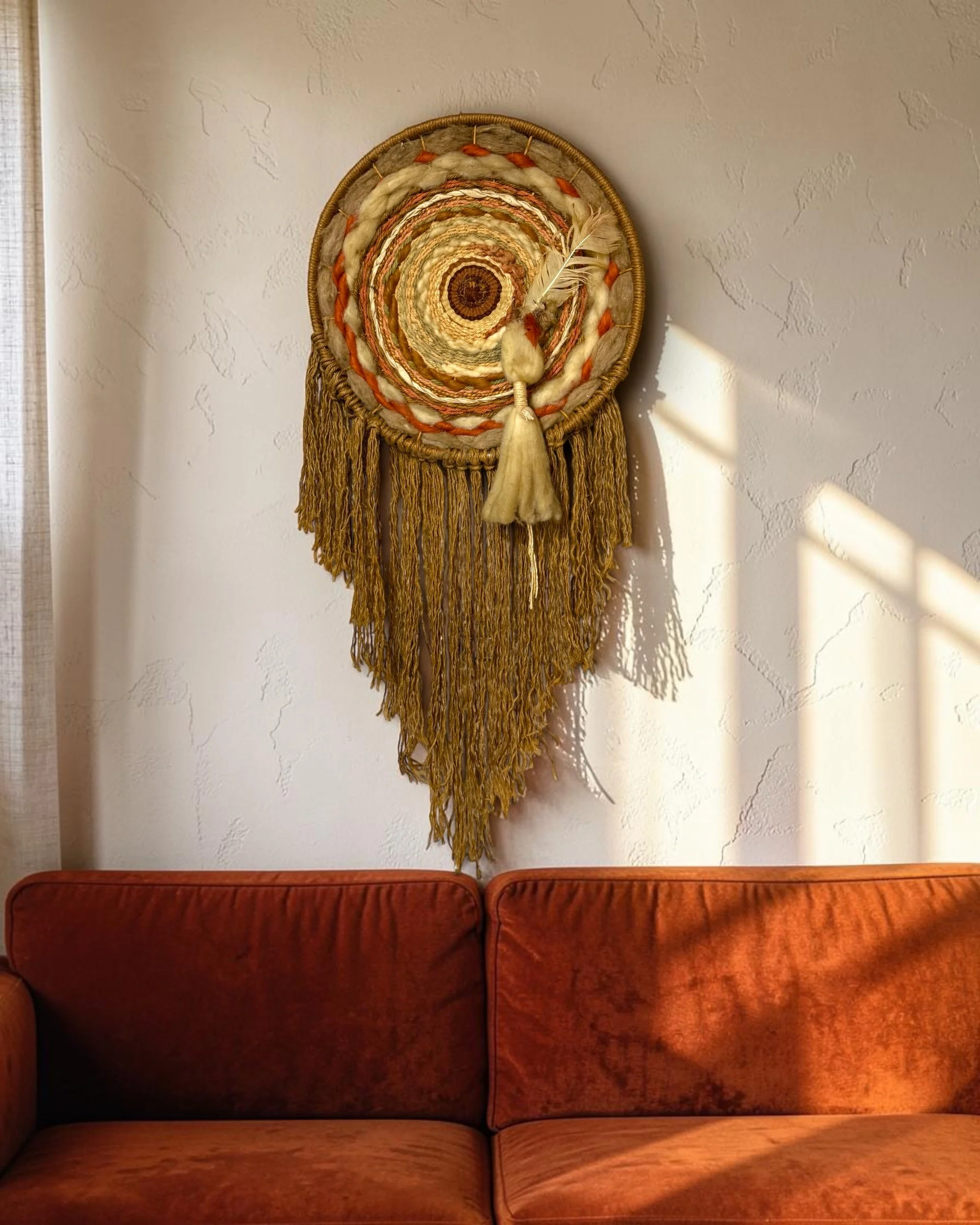 vintage boho macrame woven textile oversized hanging above an orange velvet couch