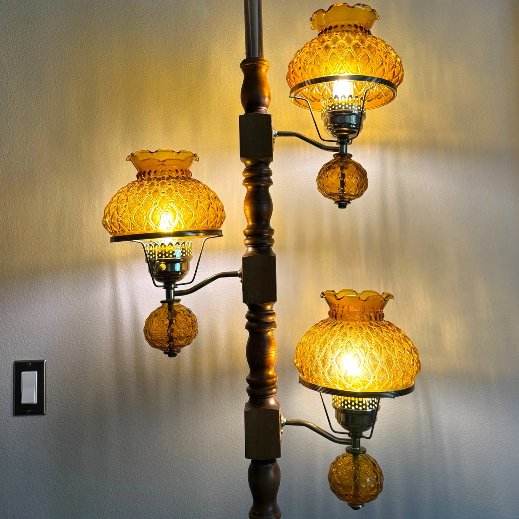 Vintage mid century modern tension pole floor lamp shown on with 3 arms, amber quilted ruffle glass shades, wood and metal.