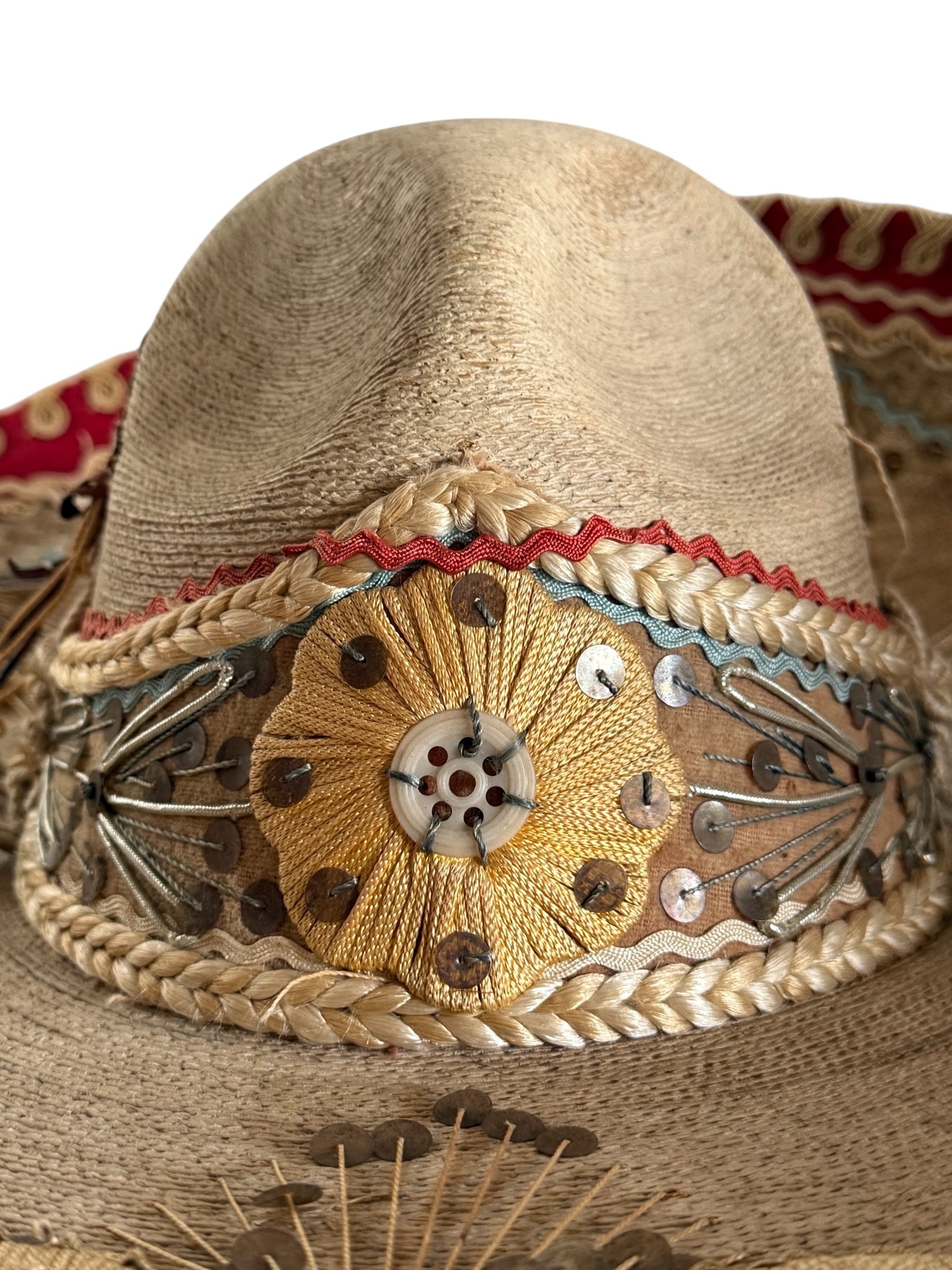 close up view of front of high crown on vintage charro sombrero showing decorative details and palm weave texture