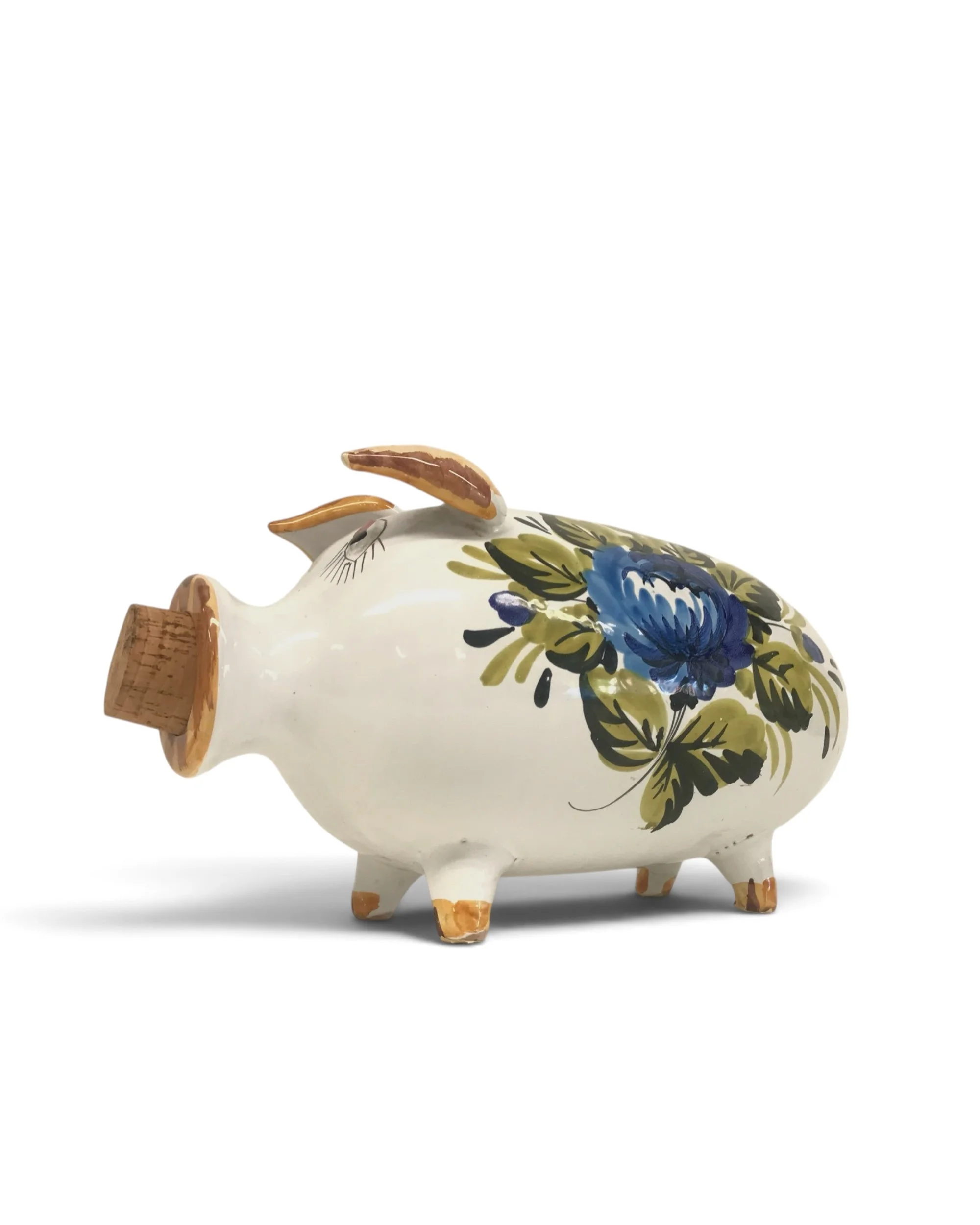 A white ceramic pig with a cork stopper, hand-painted design of a large blue flower surrounded by green leaves.