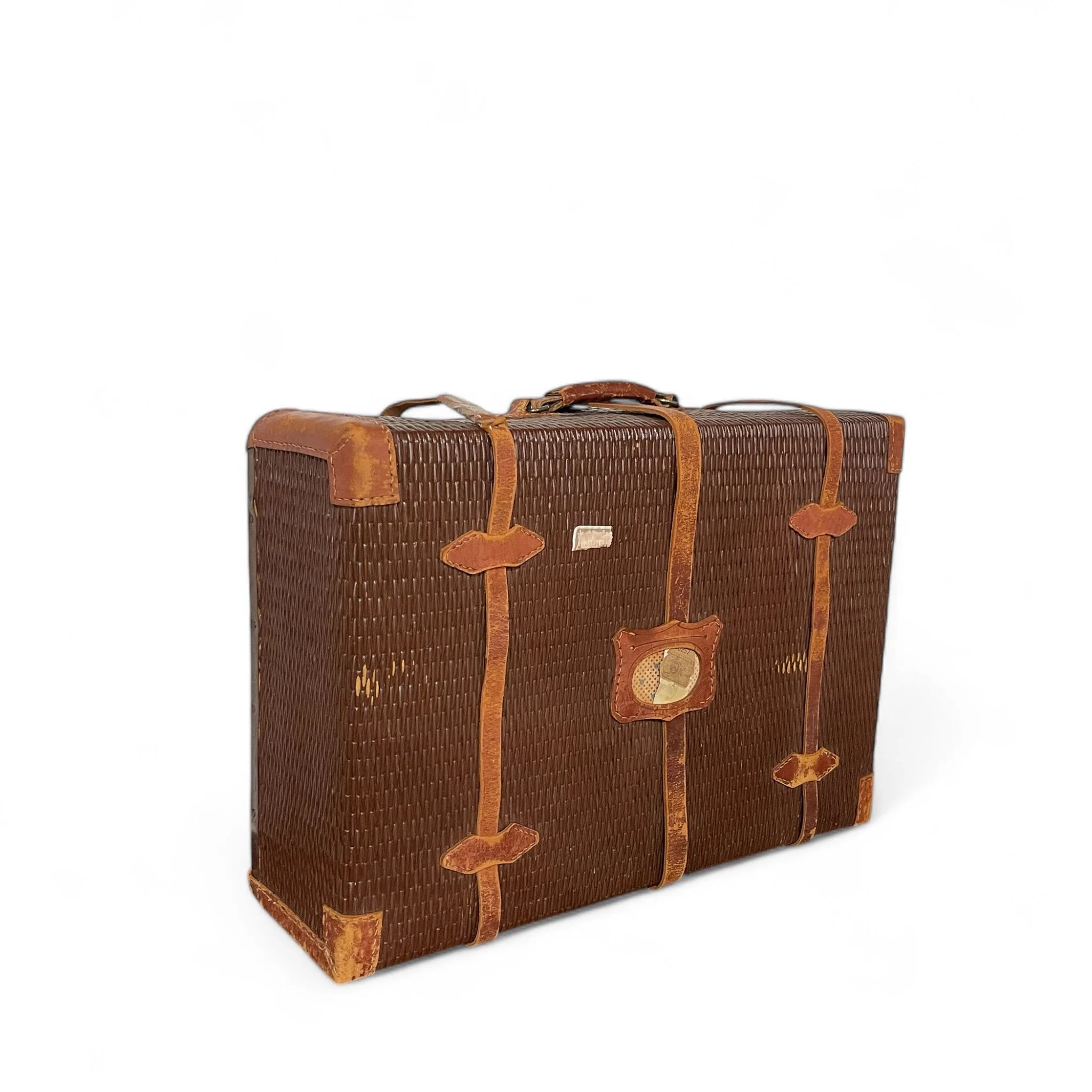 An antique rattan travel suitcase with leather corners and straps, flower pattern cloth interior, featuring parts of The Yamato and United States Customs Service travel stickers. Unique decor item.