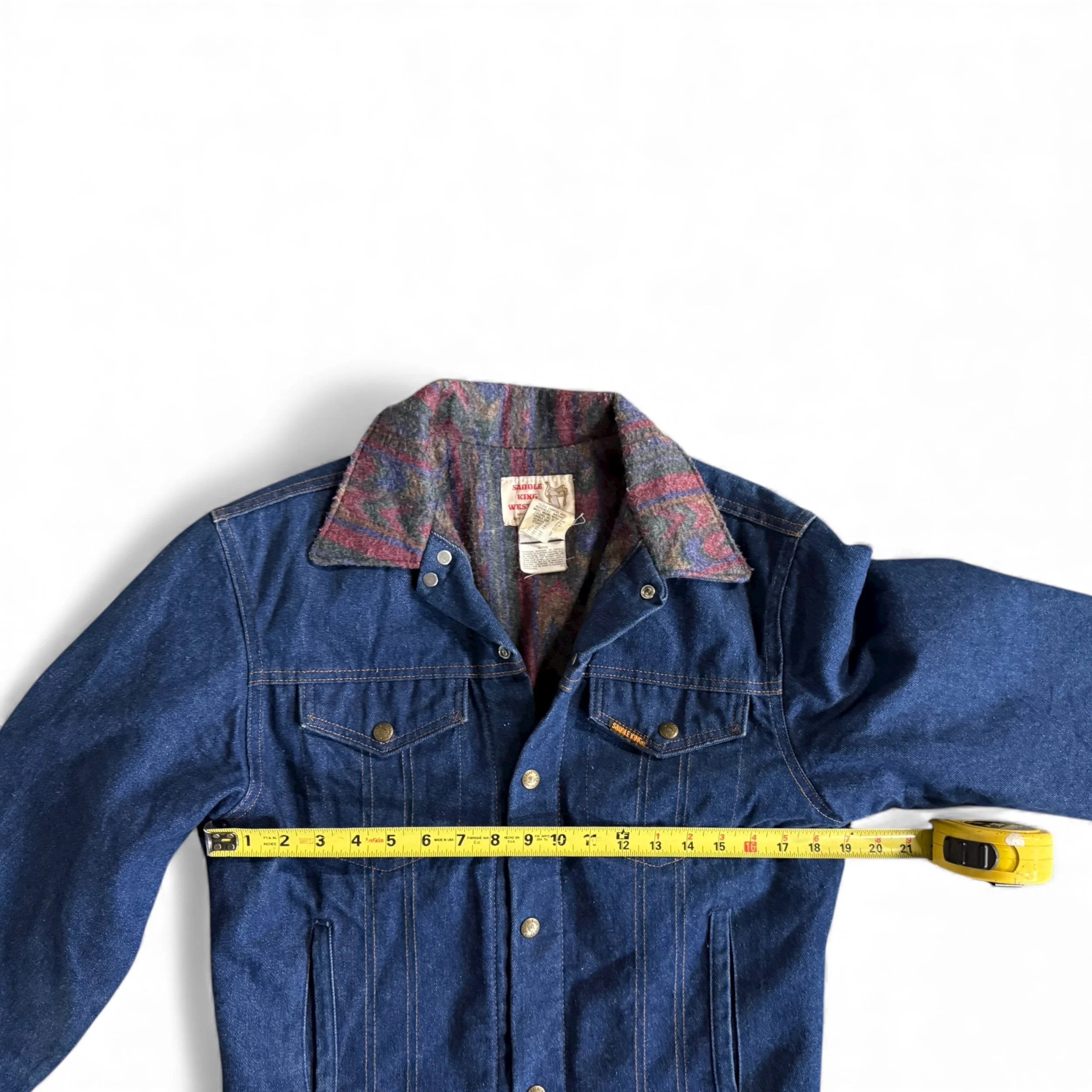 Flat lay of vintage Saddle King blanket lined denim jacket with ruler across chest showing 19" measurement
