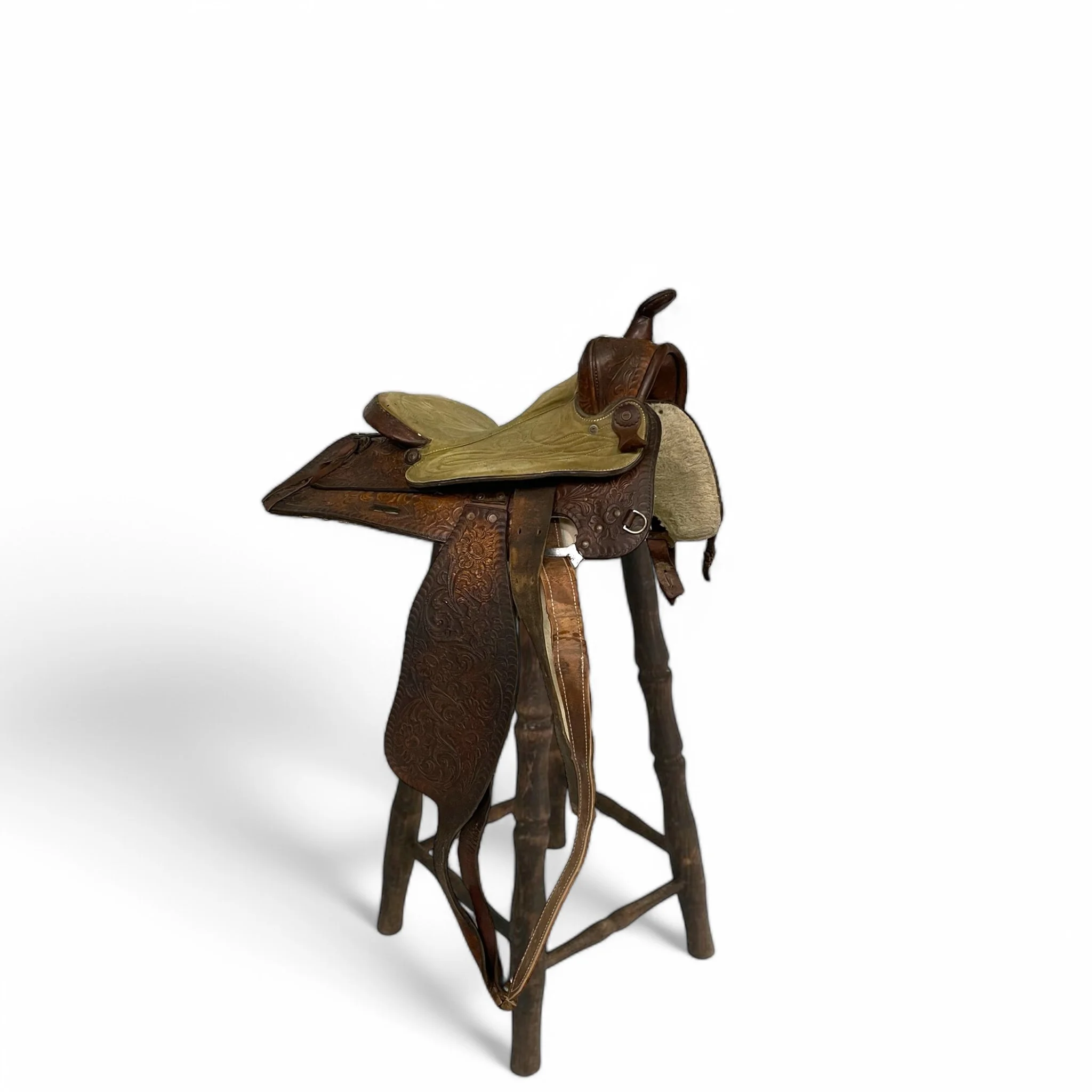 Vintage brown Western tooled leather horse saddle with green padded suede seat, perfect for trail riding or ranch, lodge, and cabin decor.