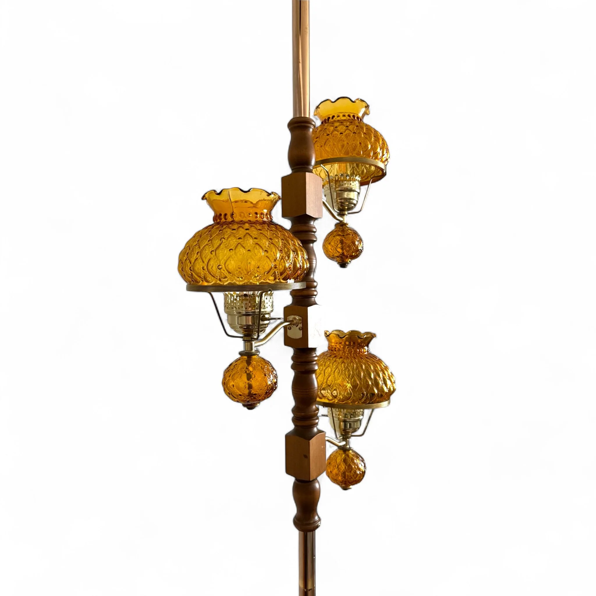 Side view of a 3-arm MCM tension pole lamp with warm amber glass shades and wood accents
