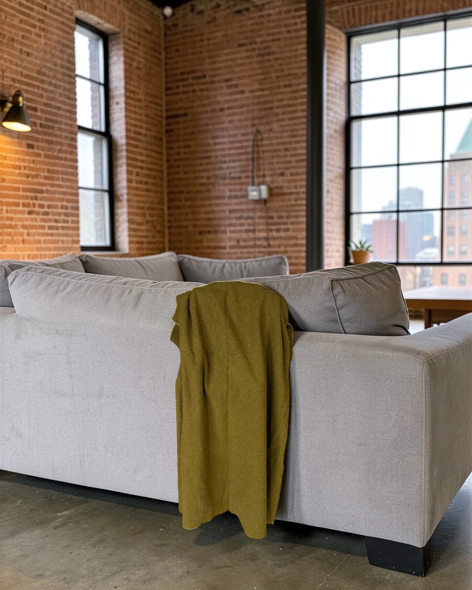 authentic army wool blanket olive drab vintage military field blanket shown styled on back of sofa in an industrial loft
