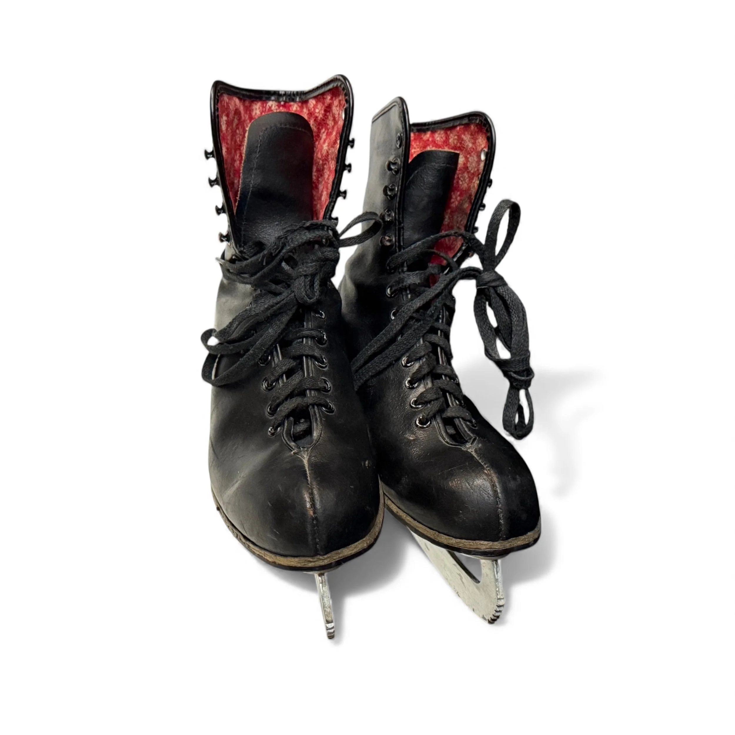 Front view of a pair of vintage black leather ice skates with metal blades, featuring red white snowflake pattern lining, mid century modern winter decorations.