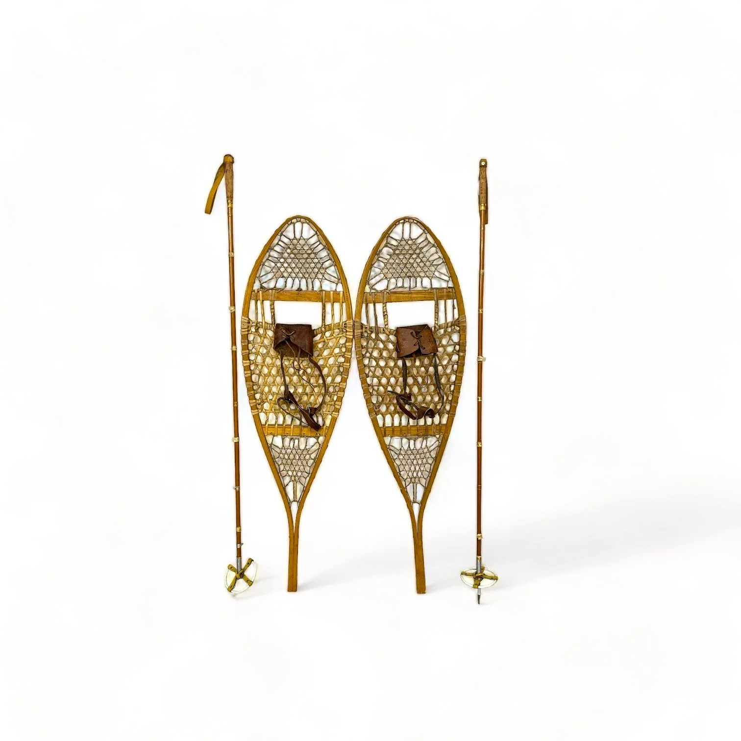 Pair of vintage wooden snowshoes with ski poles made of bamboo and cork - classic rustic winter gear perfect for cabin decor, lodge style, or outdoor adventures.