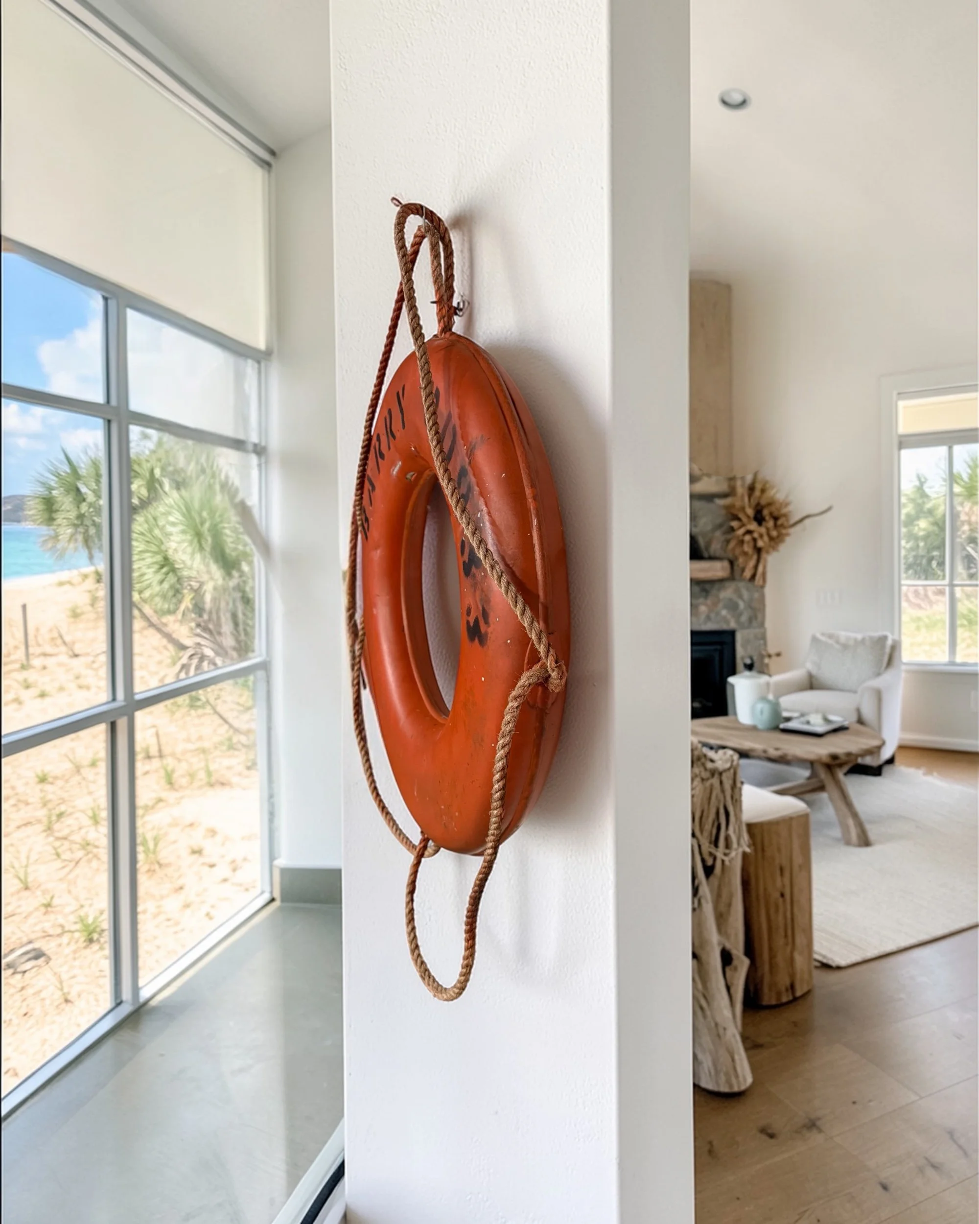 Side angle of ship life ring showing rope and surface wear hanging on the wall of a modern beach house