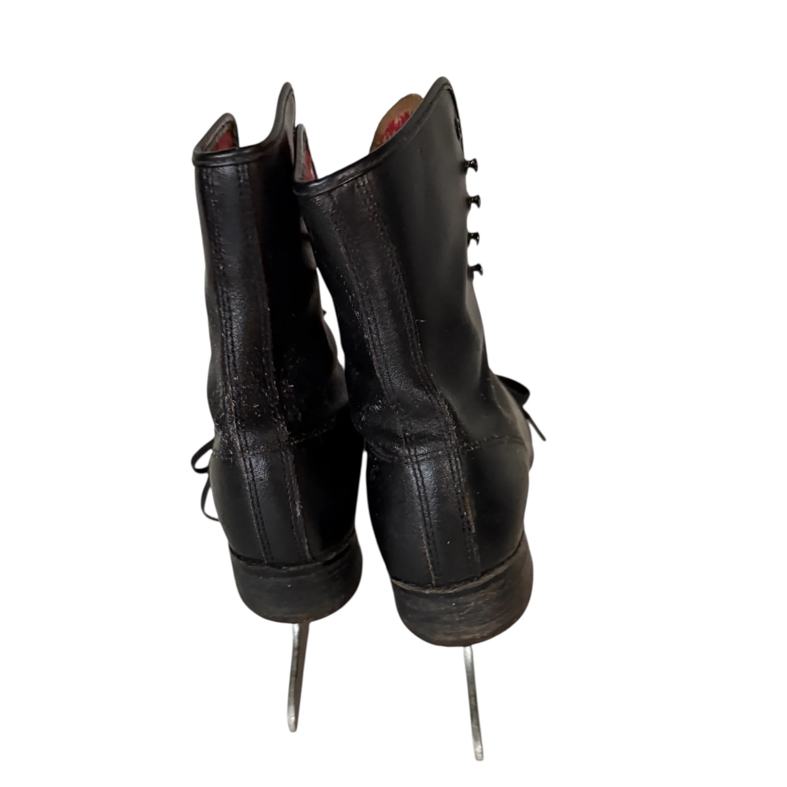 Back view of a pair of vintage black leather ice skates with metal blades, featuring red white snowflake pattern lining, mid century modern winter decorations.