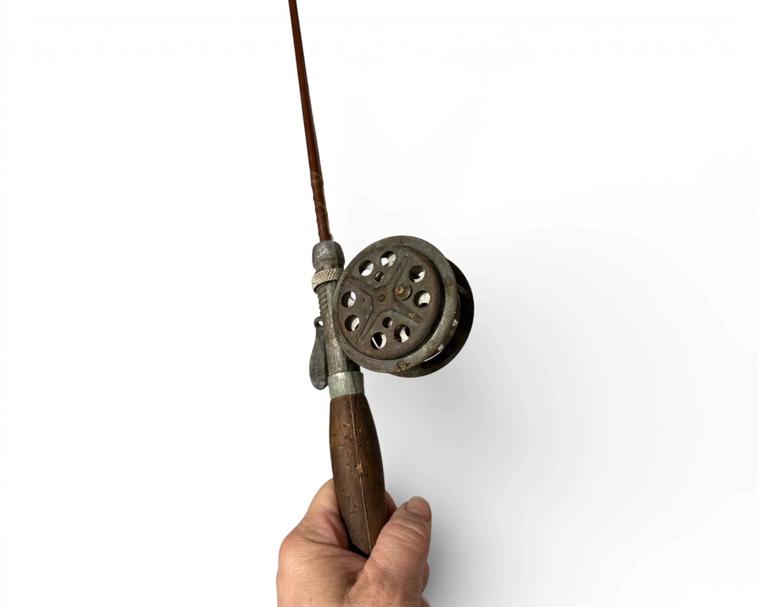 Vintage fishing pole and reel held in hand showing scale and condition