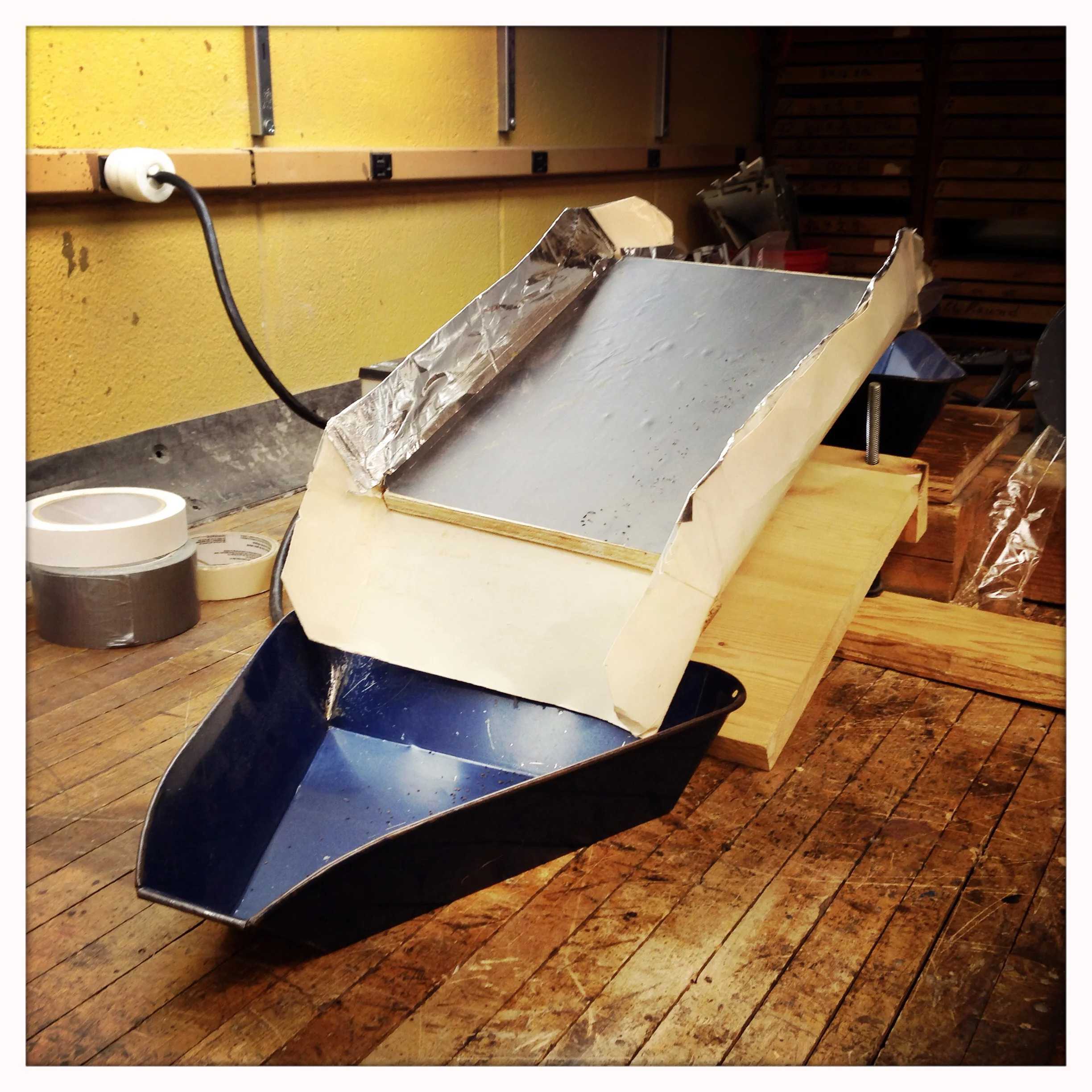 Makeshift vibratory deck separator (design by Alan Gaul). Easily-rolling objects, such as round seed, collect down into the lower blue tray while remaining objects vibrate upwards over the plate.