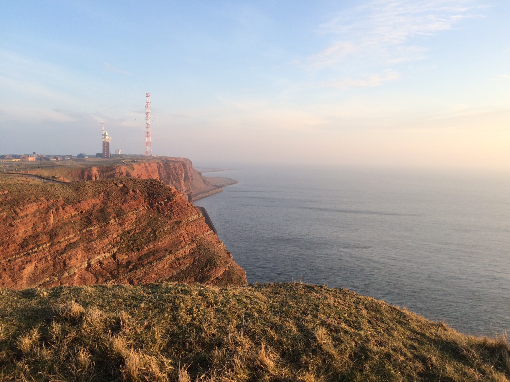 Red sandstone cliffs are framed by blue ocean.