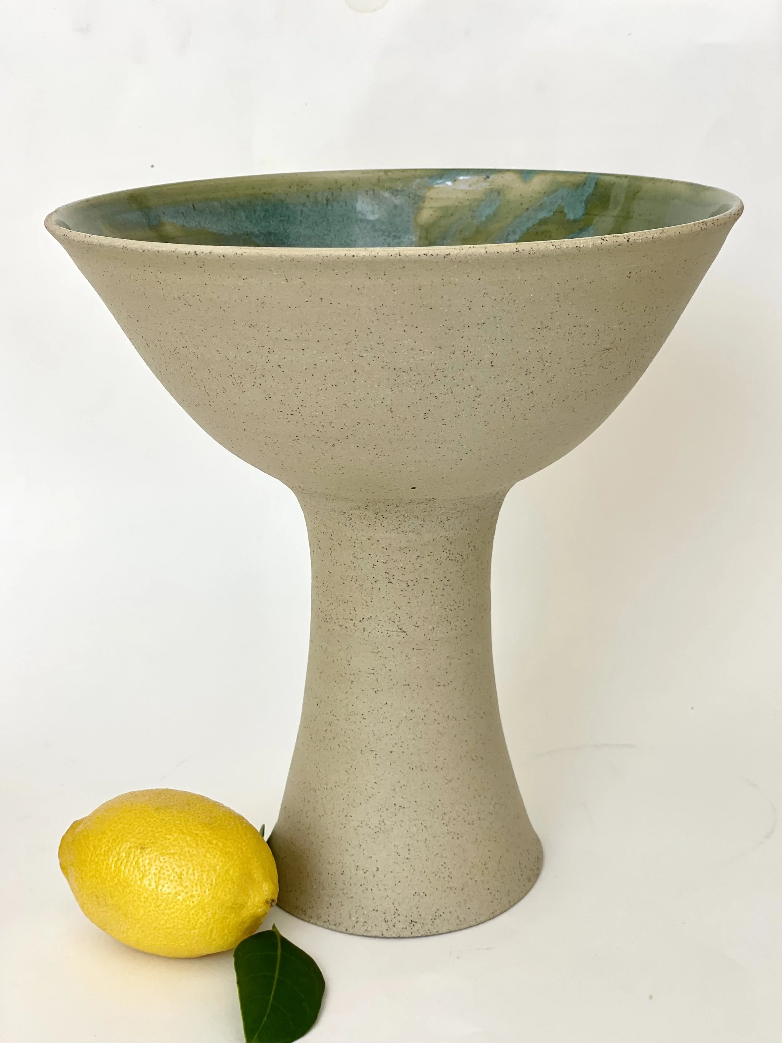 Tall ceramic pedestal bowl with green interior glaze and raw clay exterior | Handmade