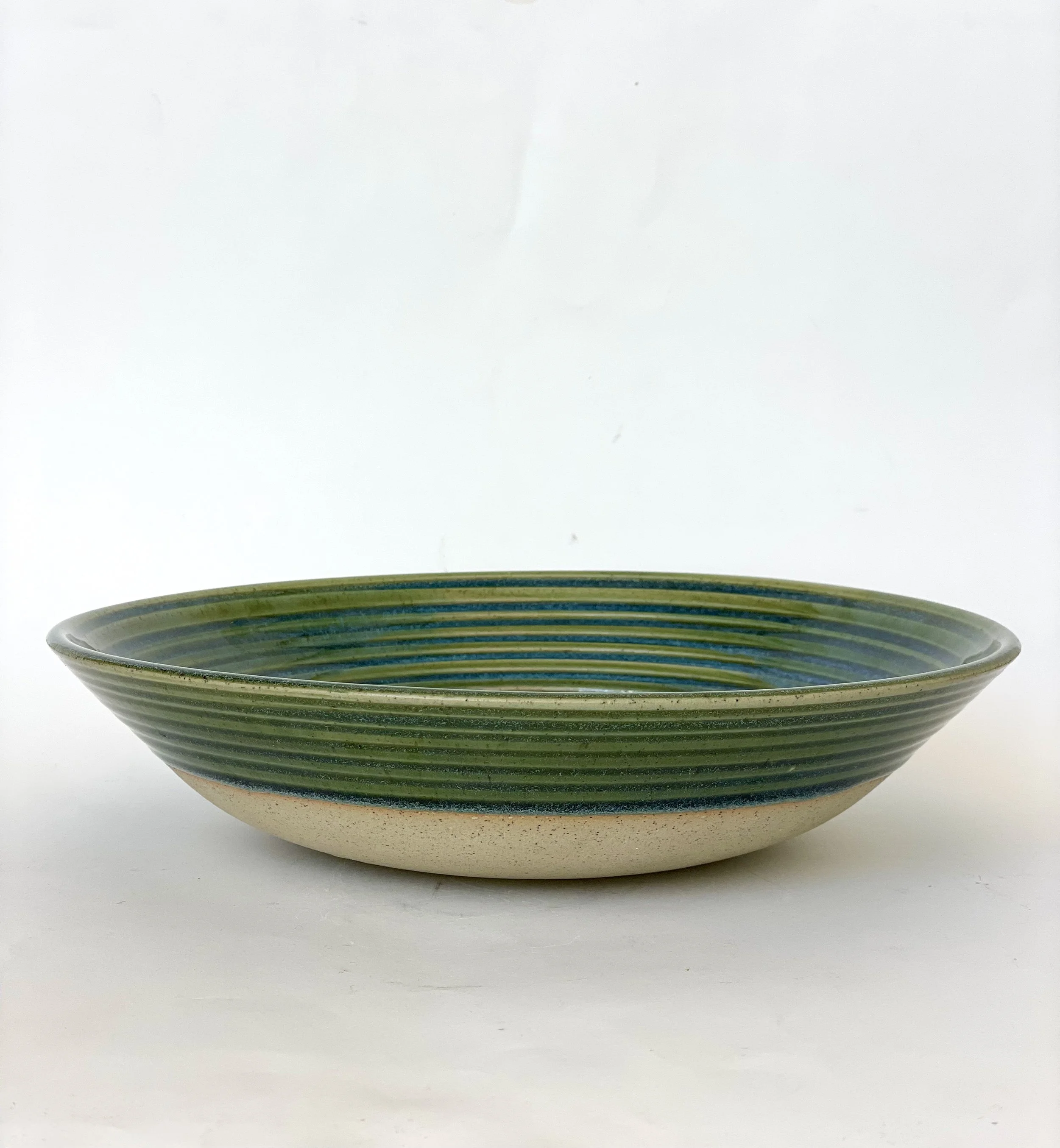 handmade green ceramic serving dish with a raw clay base and blue rings