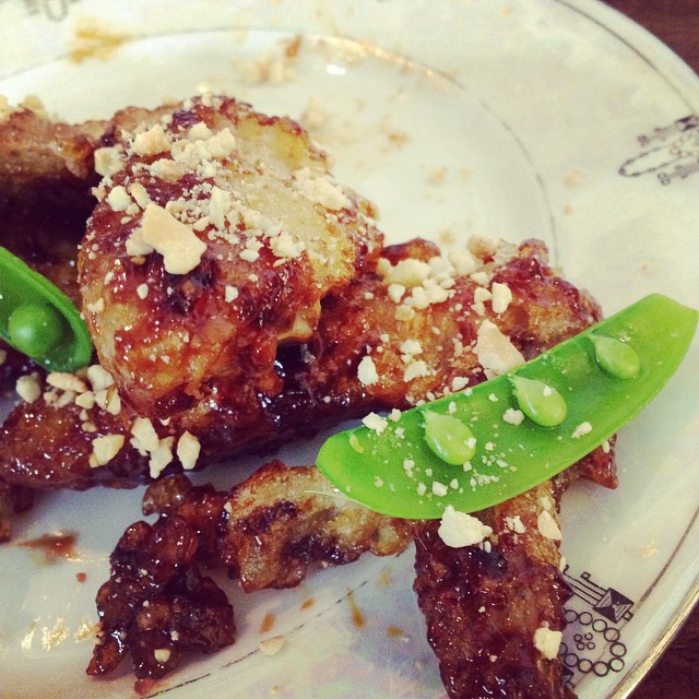 Korean fried chicken wings with cashews and fresh peas.