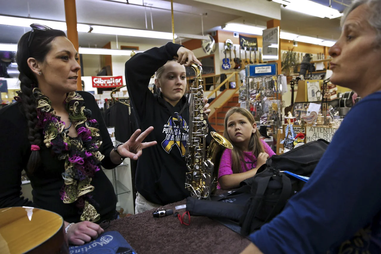  Cathy instructs Makenzi Carpenter, 11, (center) how to properly take care of her saxophone, while Makenzi's mother, Erica White, (left) and cousin, Honey Ray Abrams, 9, listen. 