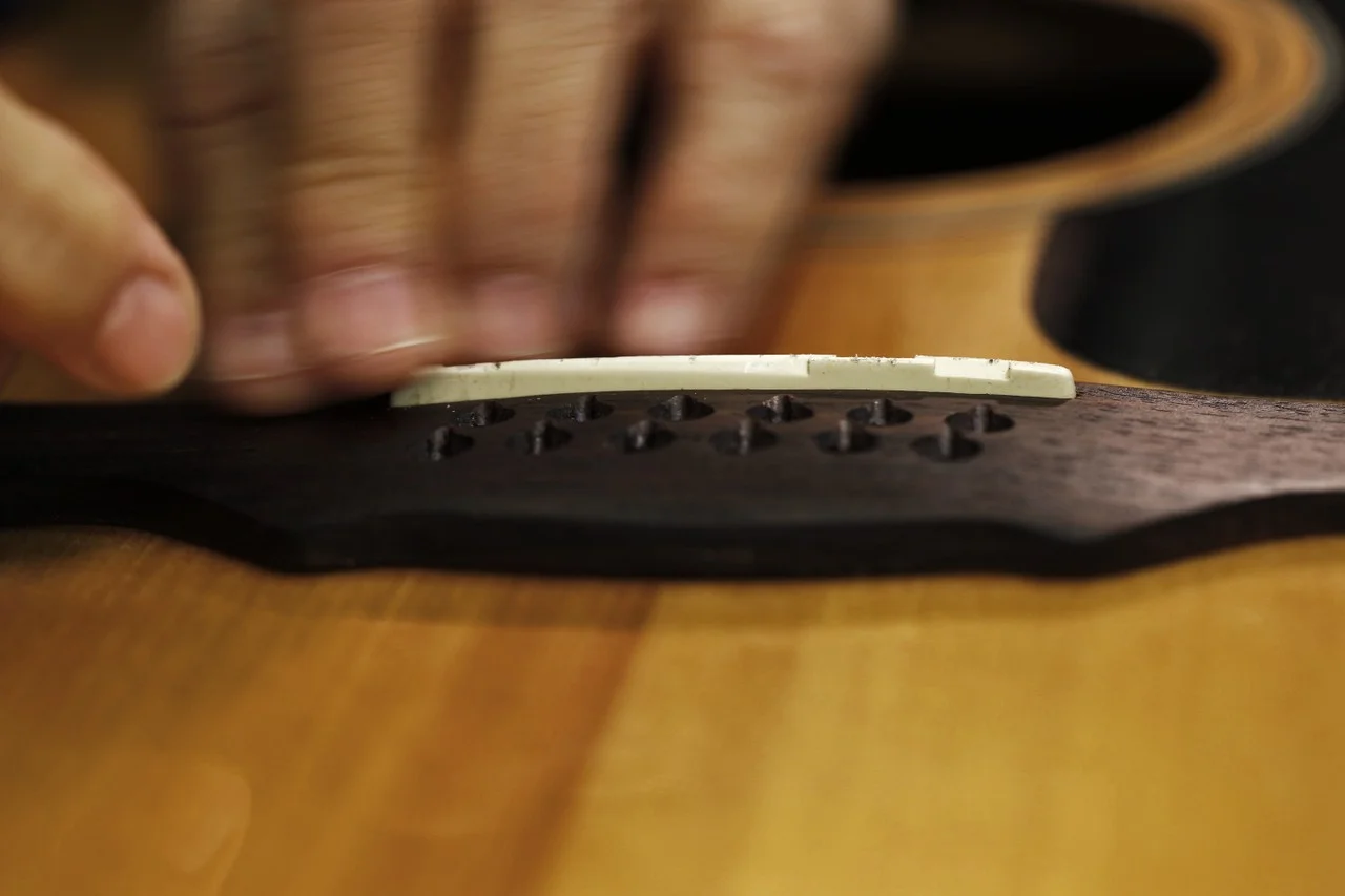  Cathy fits a new bone for an old, damaged guitar. Cathy carefully sanded the bone in order to get a perfect fit. Guitar strings rest on the bone, so it must be fitted properly. 