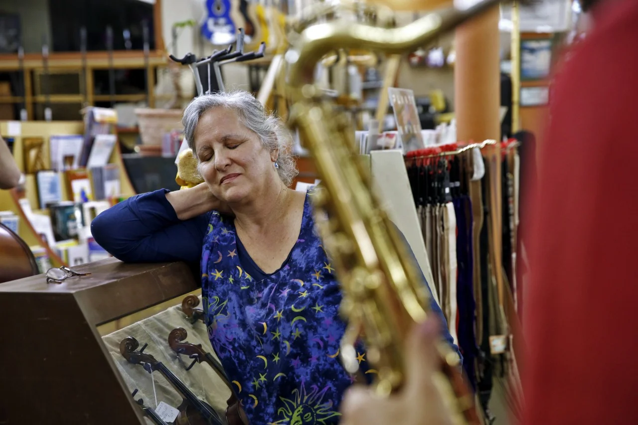  Cathy listens while Danny Markovitch plays the crooked soprano saxaphone during an impromptu jam session in the store. Danny, a musician orginally from Israel, is traveling throughout Kentucky with his band, Marbin. They stopped in the shop to look 