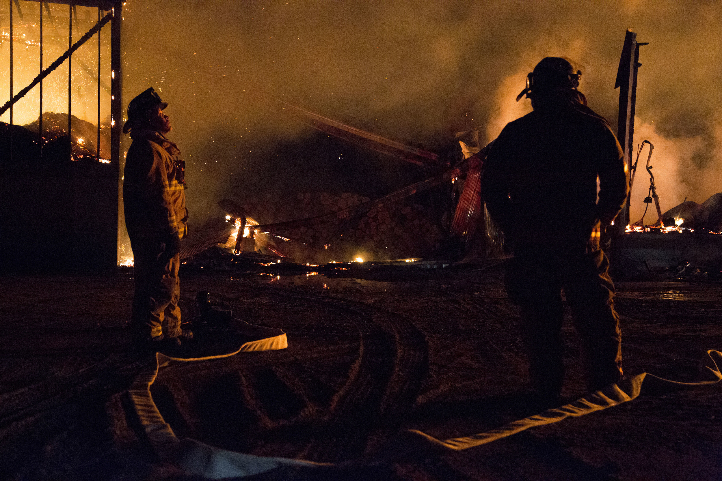  Hartford firefighter Zach Bowley, left, and Fairlee firefighter Geoffrey Mallett watch as firefighters from across the Upper Valley fight to put out a four-alarm fire at Britton Lumber Co in Fairlee, Vt., on Saturday, March 28, 2015. 