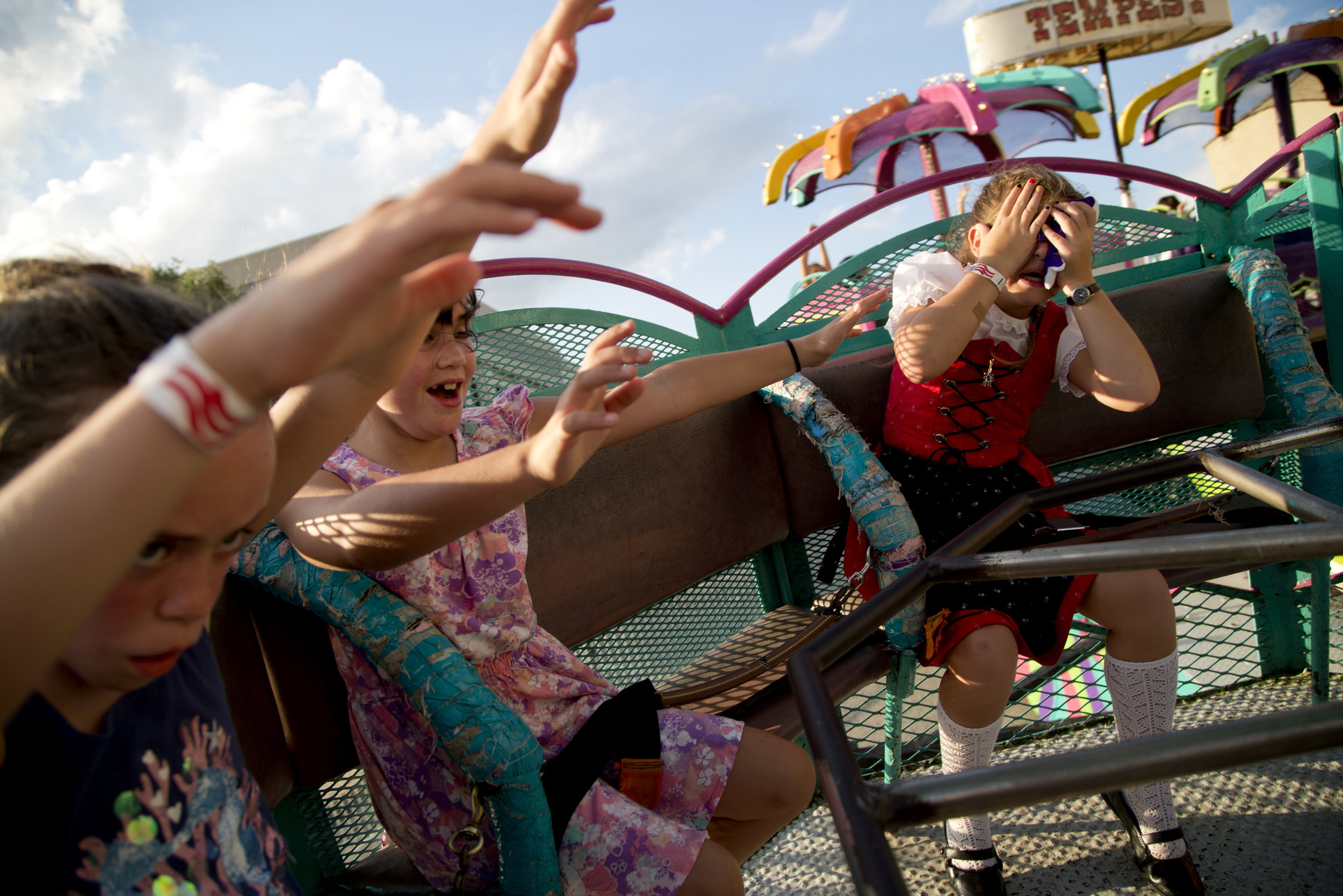 Little Miss Strassenfest Kennedy Kunkel of Jasper, 8, right, covered her eyes after getting dizzy on the Tempest carnival ride during Strassenfest in Jasper on Saturday. Ava Claire Werne of Jasper, 8, left, and Tessa Werne of Jasper, 7, tried to keep their hands in the air for the entire ride. 