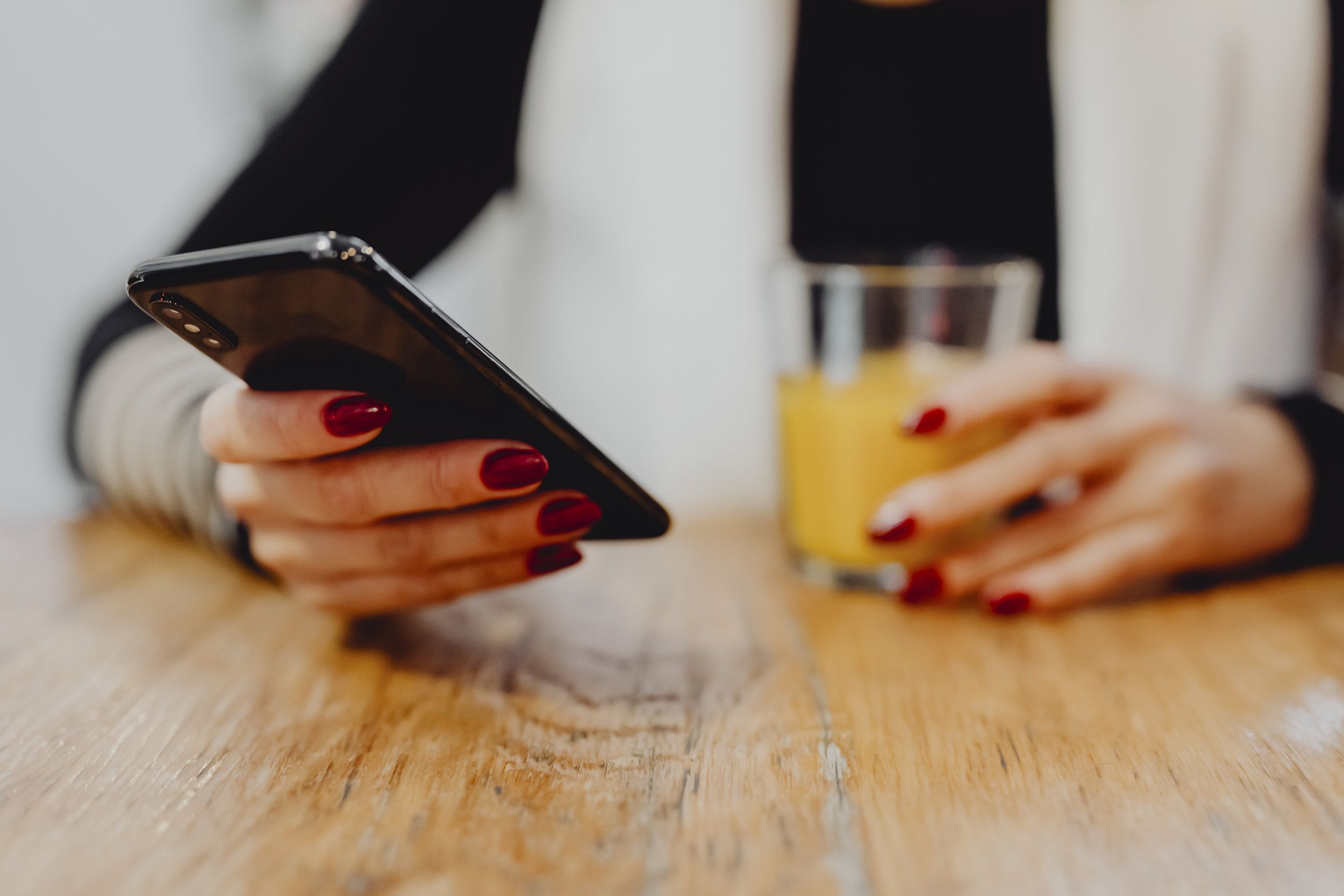 Woman having a glass of juice and checking her phone