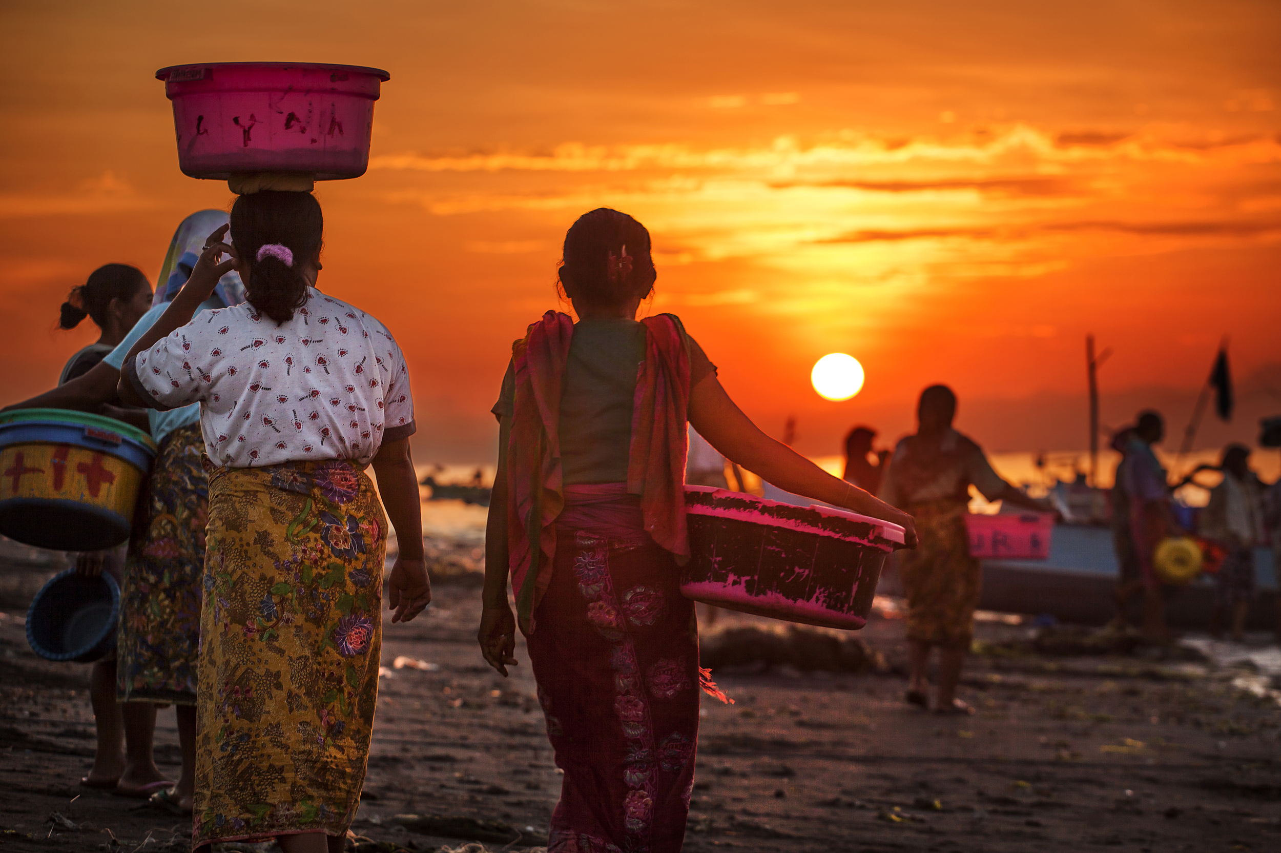  Woman walk down to shore as the fishing boats come in at Tanjung Luar, Lombok 