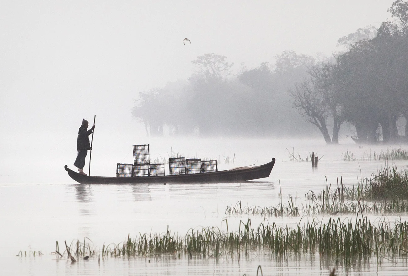 fisherman coming with the fish traps in the early morning fog