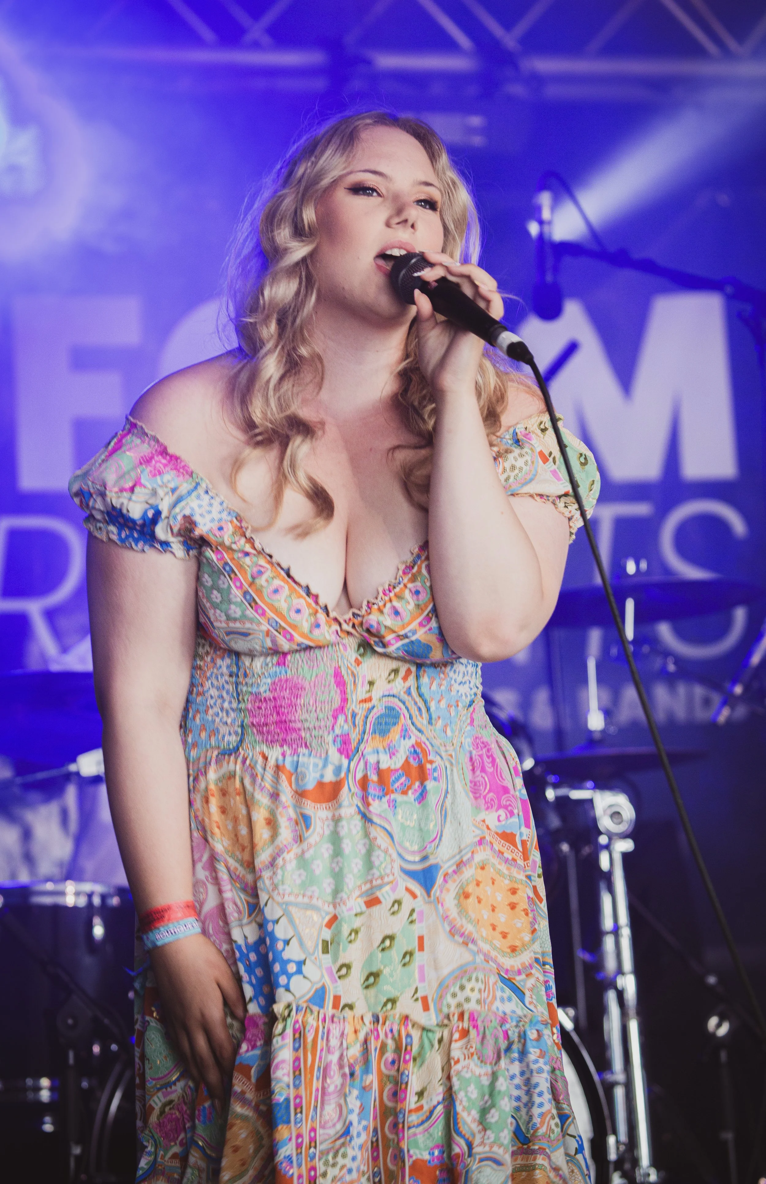 Marnie Marie playing the Platform one stage at the Isle of Wight festival singing on stage, wearing a floral dress