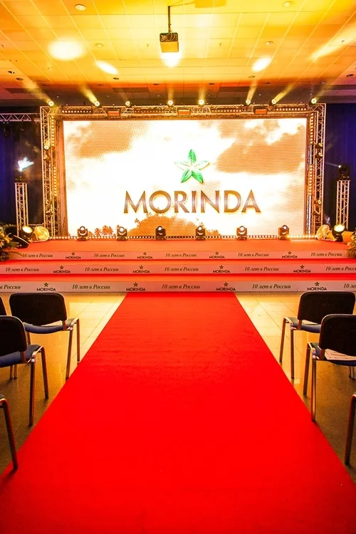 Сцена для международной компании Morinda. Брендинг торцов ступеней, красная ковровая дорожка, большой бронированный задник сцены подчеркивают статус мероприятия на любом проекте.