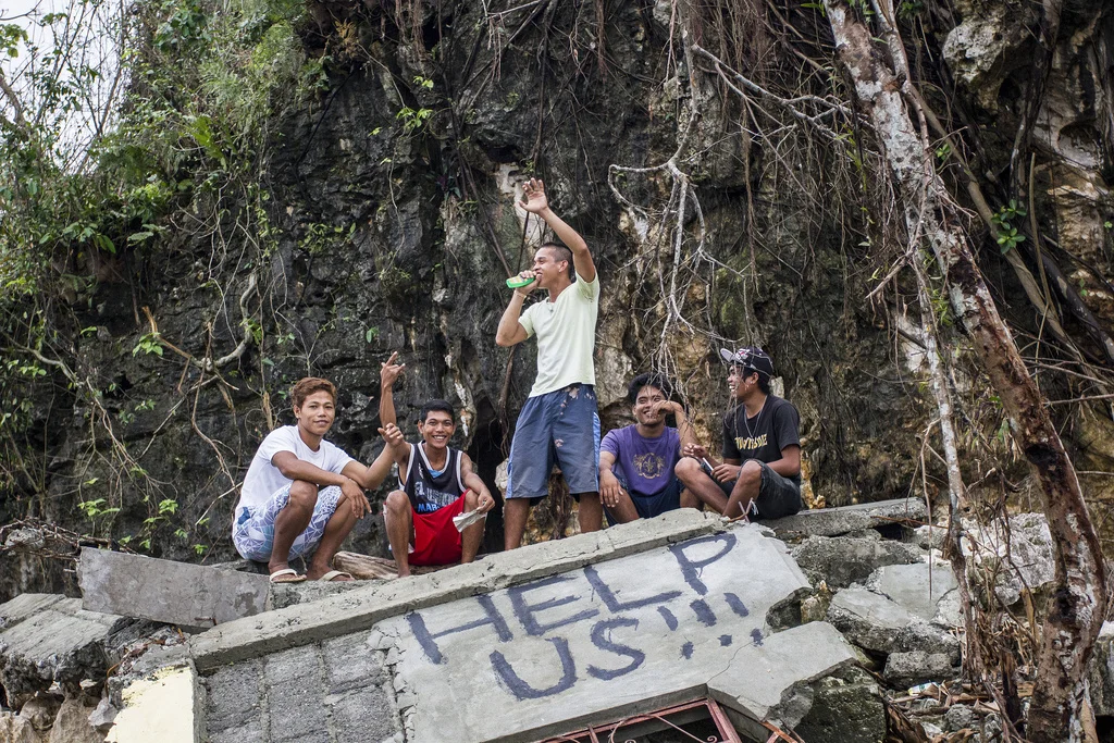 Young men in Legaspi, Samar, hang out atop the wreckage of a concrete house. Behind them stands one of the many rock formations in the region that saved hundreds of families from the six metre storm surge of Typhoon Haiyan. 