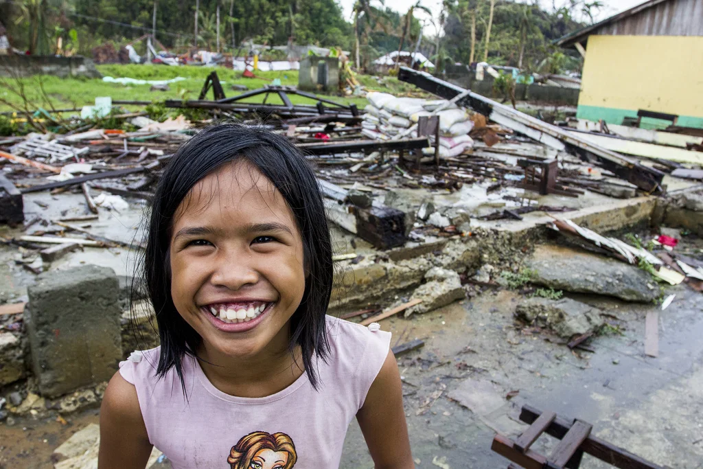 A grinning girl in front of one of the school buildings razed by Typhoon Haiyan in Veloso, Samar. 